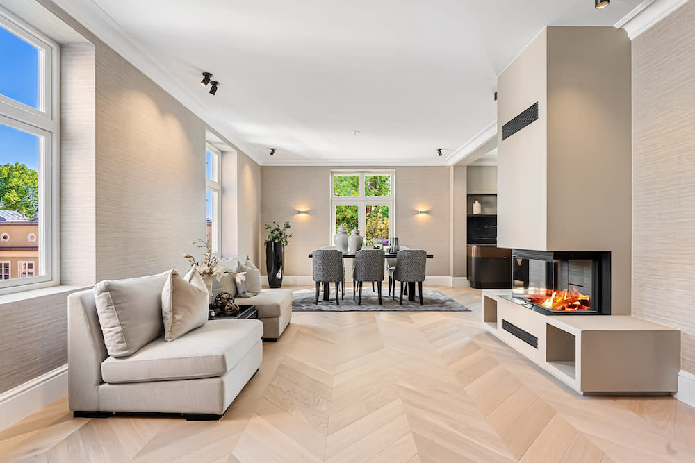 A stylish living room showcasing European oak flooring, a fireplace and a dining table, perfect for family meals and relaxation in a comfortable setting.