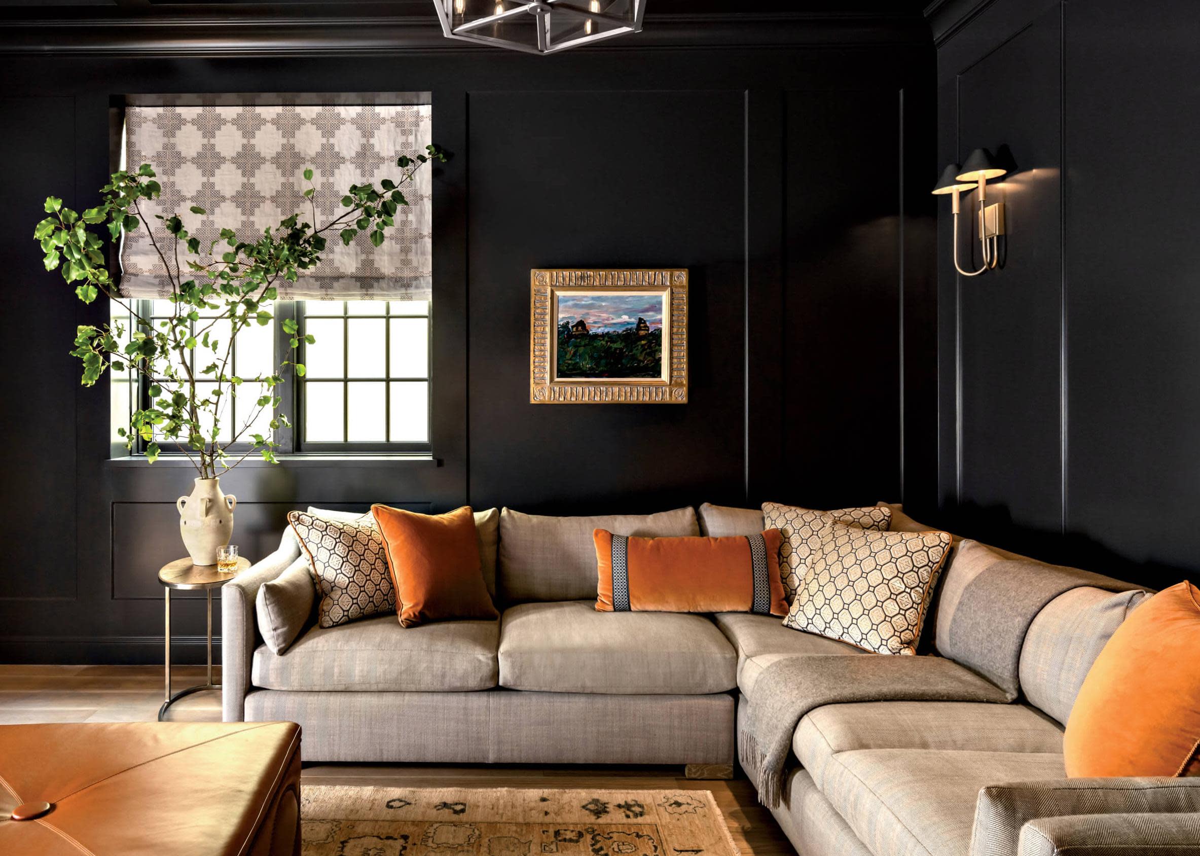 moody black living room with beige sectional with orange throw pillows