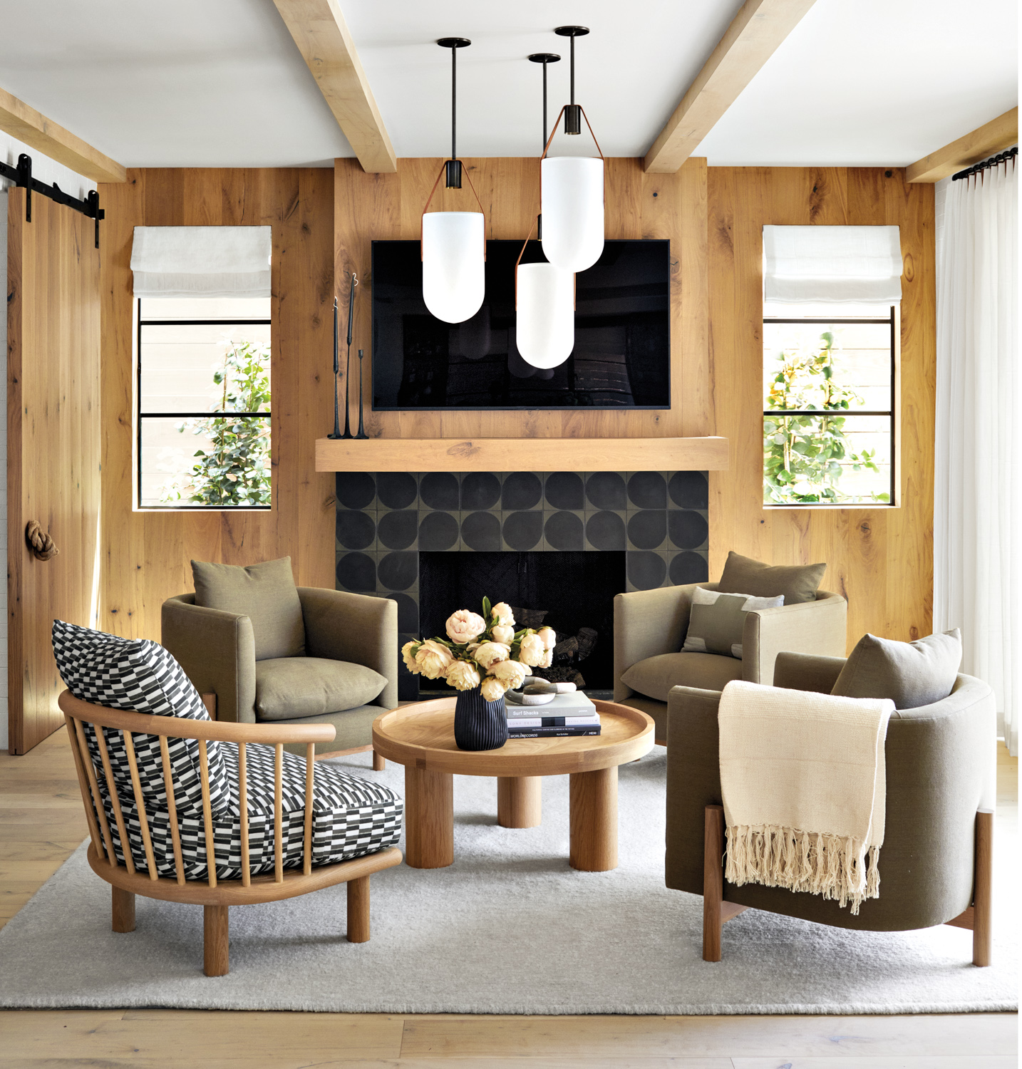 living area with three allied maker pendants, club chairs and a spindle back chair atop a alpaca rug