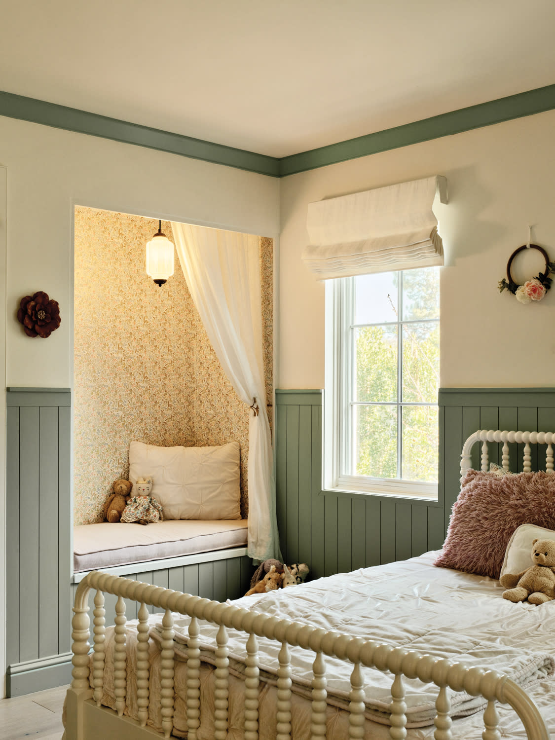 Children’s bedroom with a spindle bed, reading nook and sage green shiplap along the wall