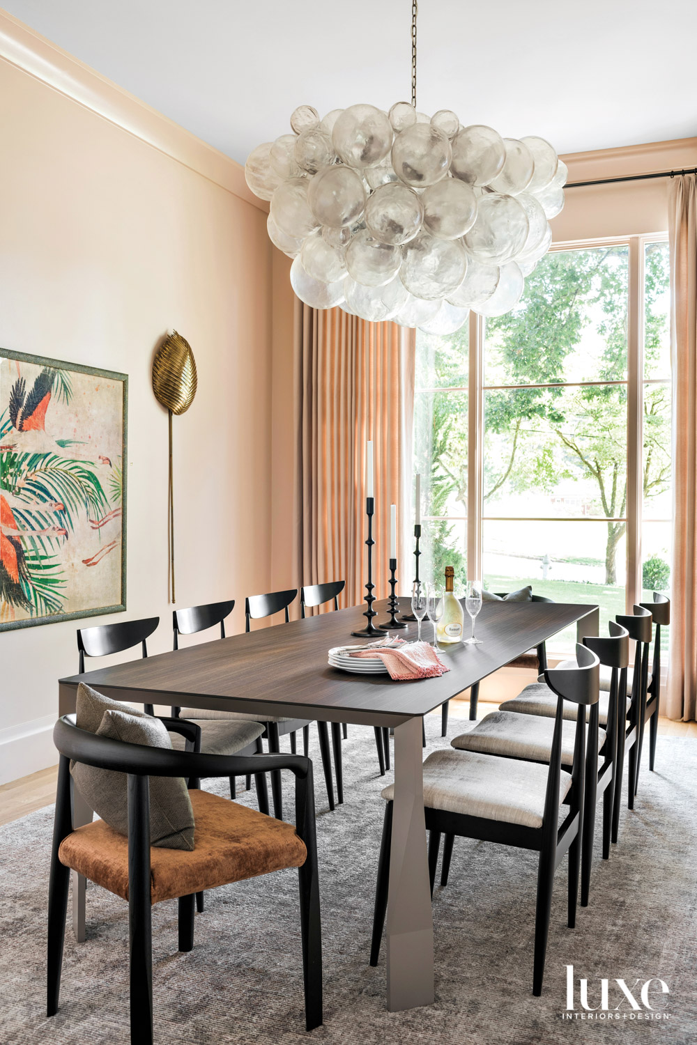 Peach-colored dining room with dark table and bubble chandelier