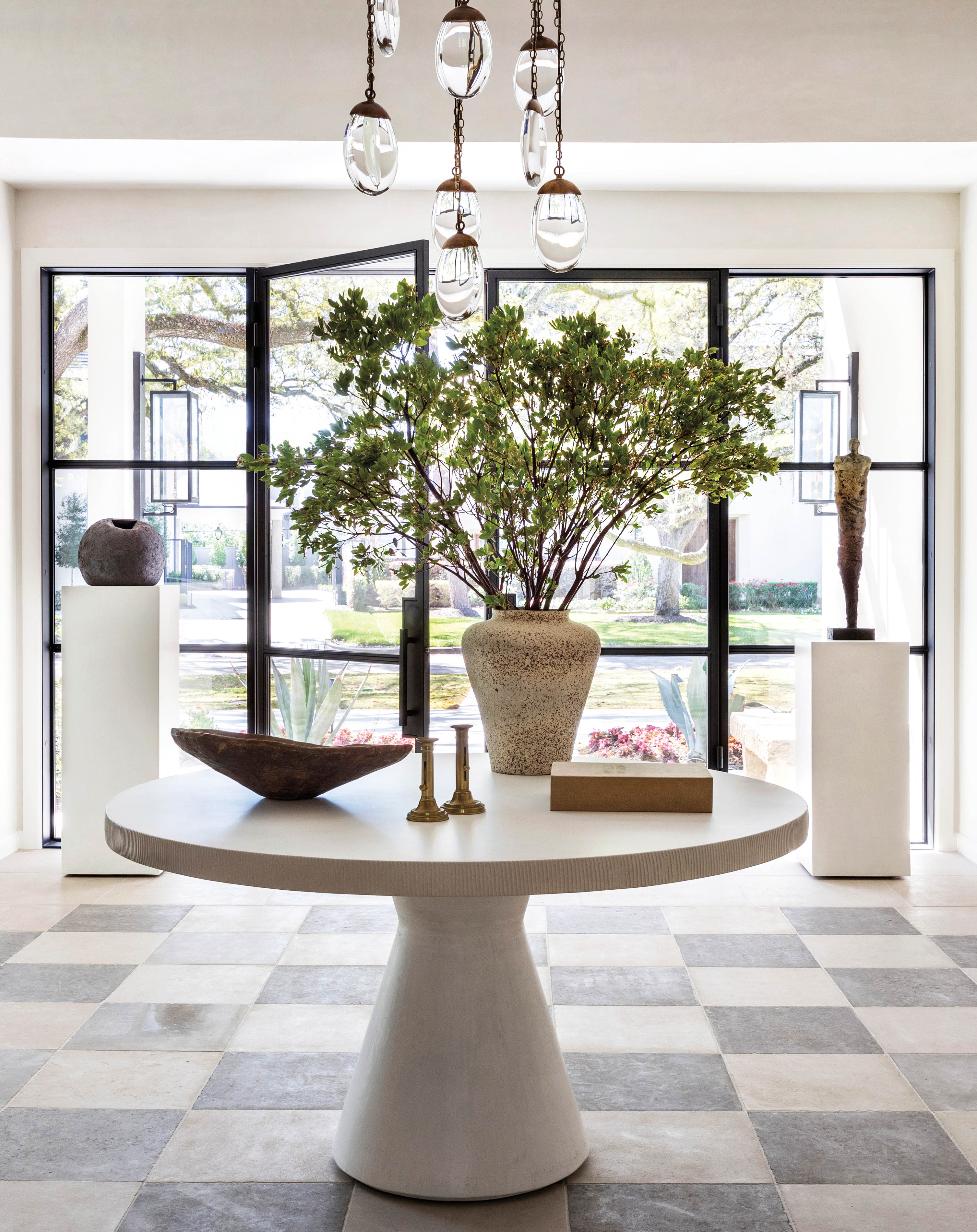 white entryway with checkerboard pattern floor and custom table with ceramic vase