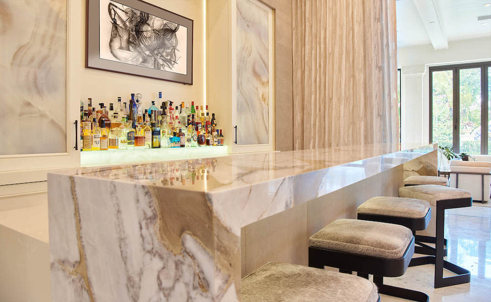 A marble bar with elegant stools positioned in front of a large, captivating picture on the wall.