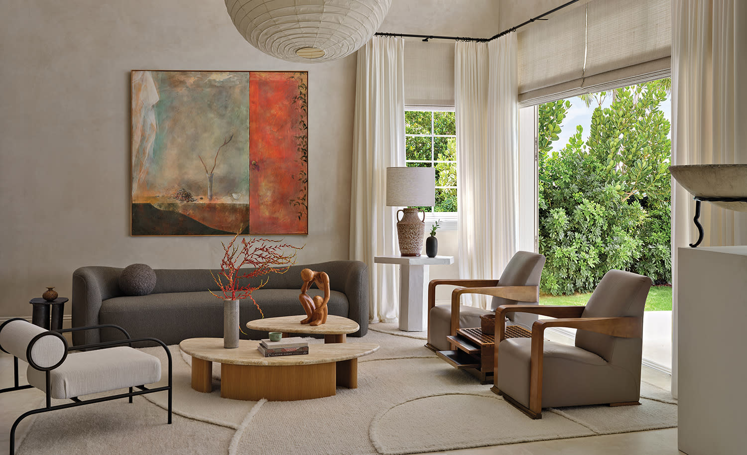 A modern living room with a neutral palette and a view of lush greenery through large windows