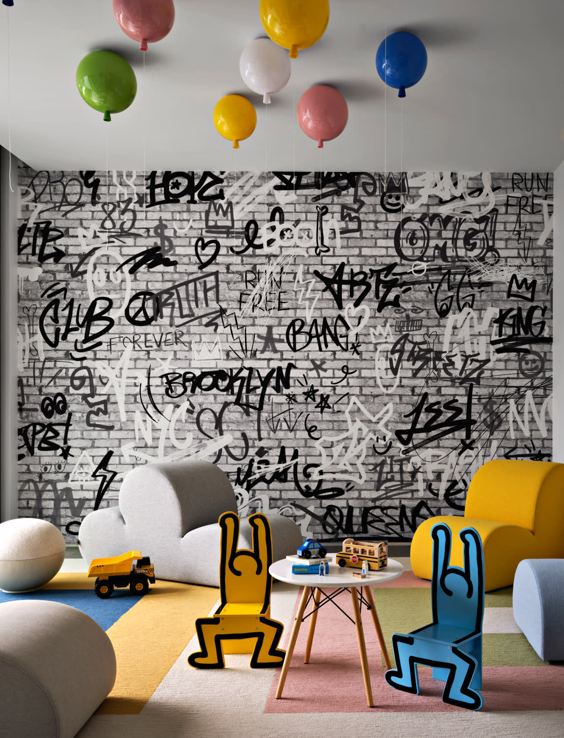 Playful kids' room with a graffiti-themed wall, colorful balloon light fixtures, and abstract furniture