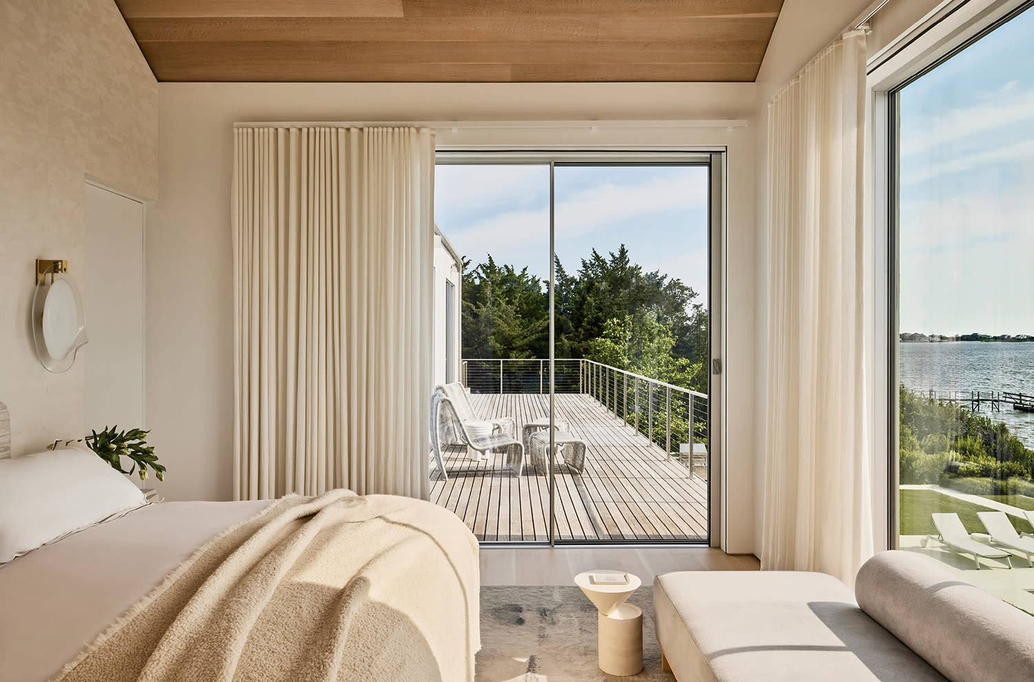 contemporary bedroom in an off-white color with views of an attached deck outside