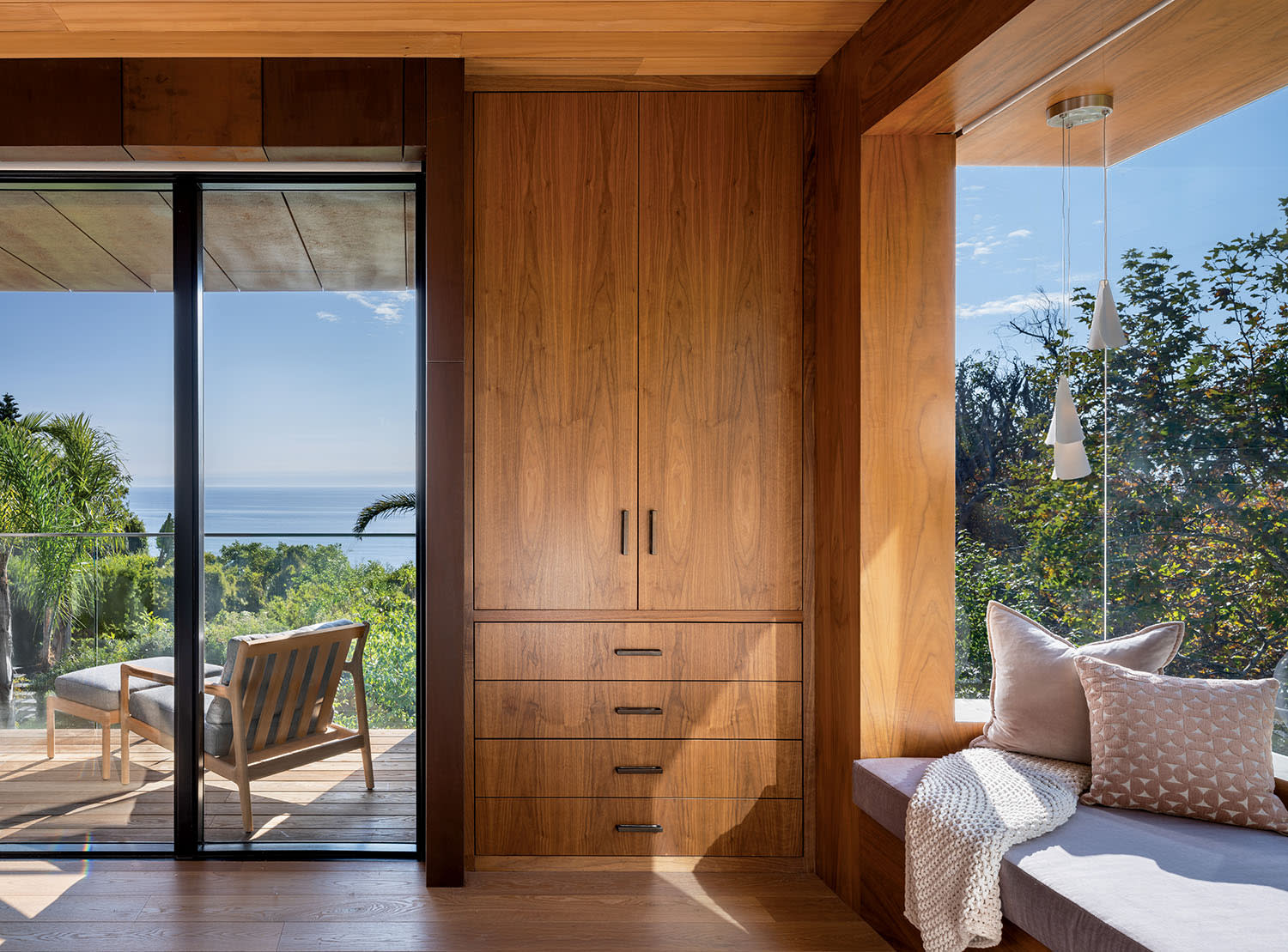 Modern room with a wooden accent wall, large sliding glass door, and cozy window seat. 