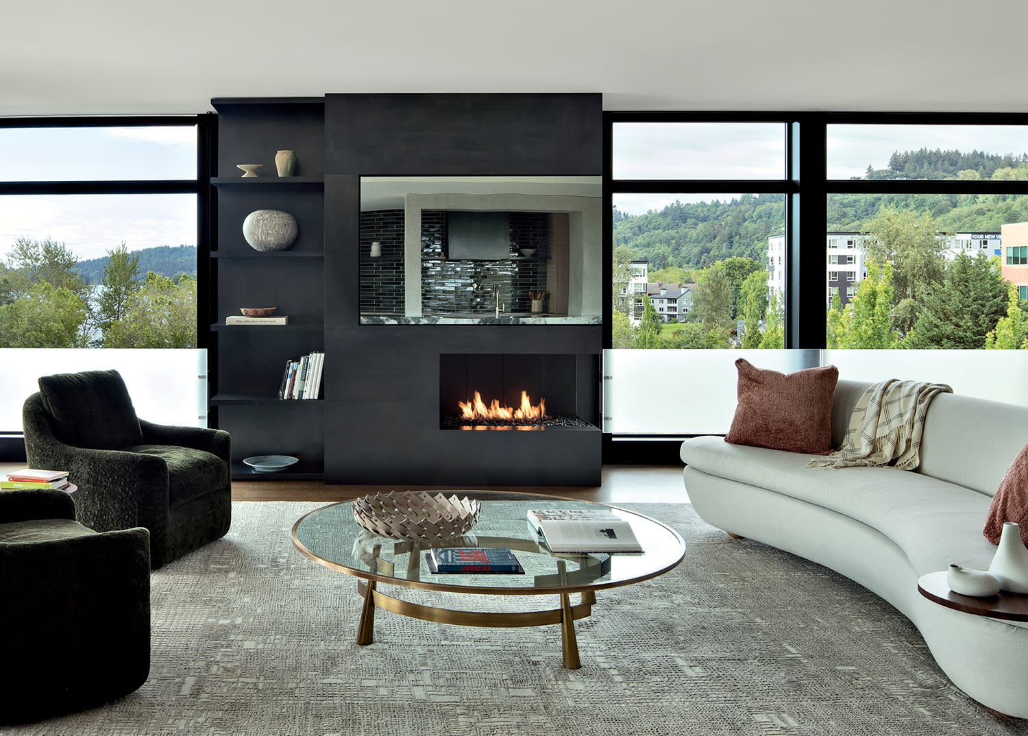 sleek living room with a black fireplace, curving sofa and views of the Wilamette River outside
