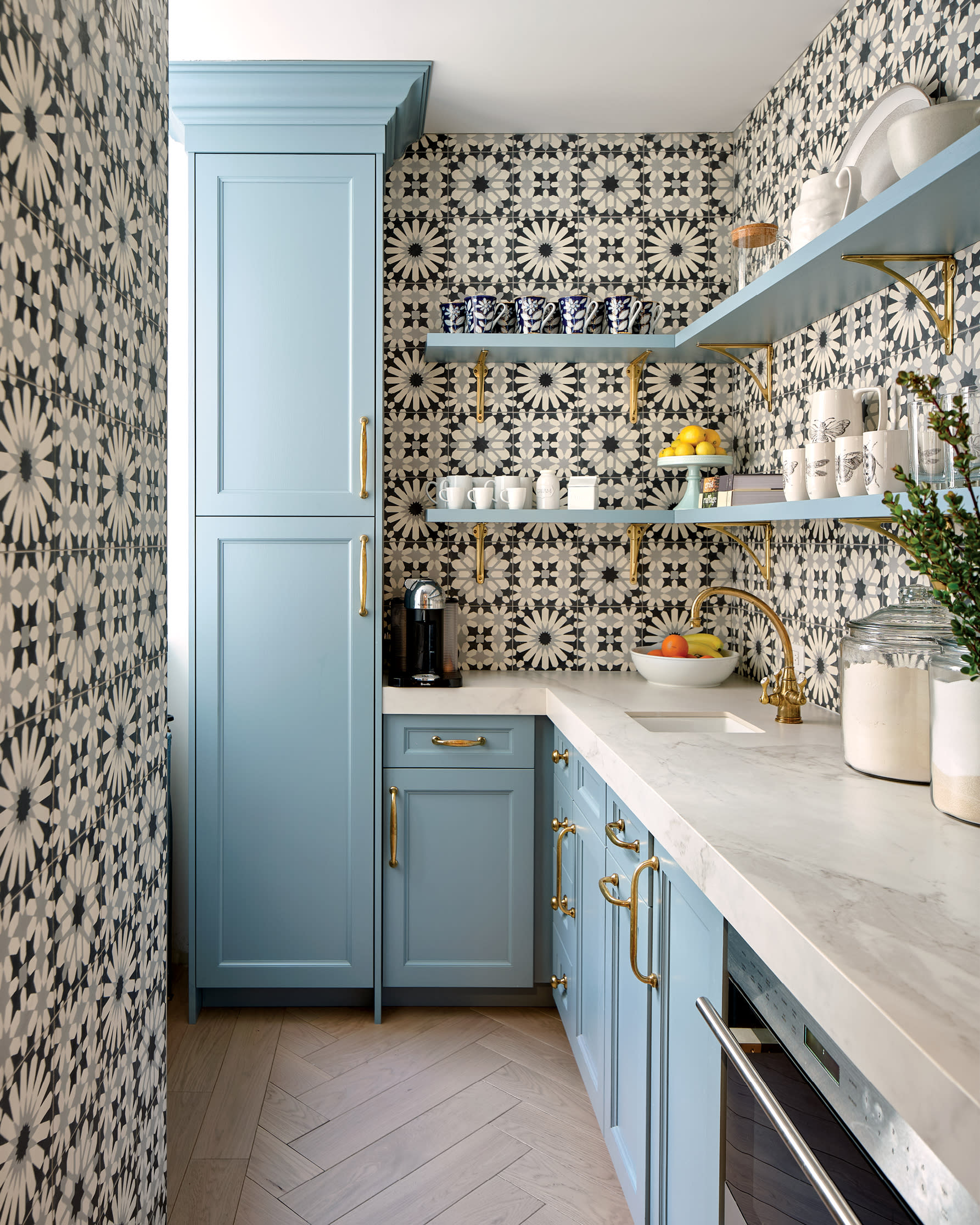 floral geometric tile wraps around blue cabinetry and marble countertops in this pantry