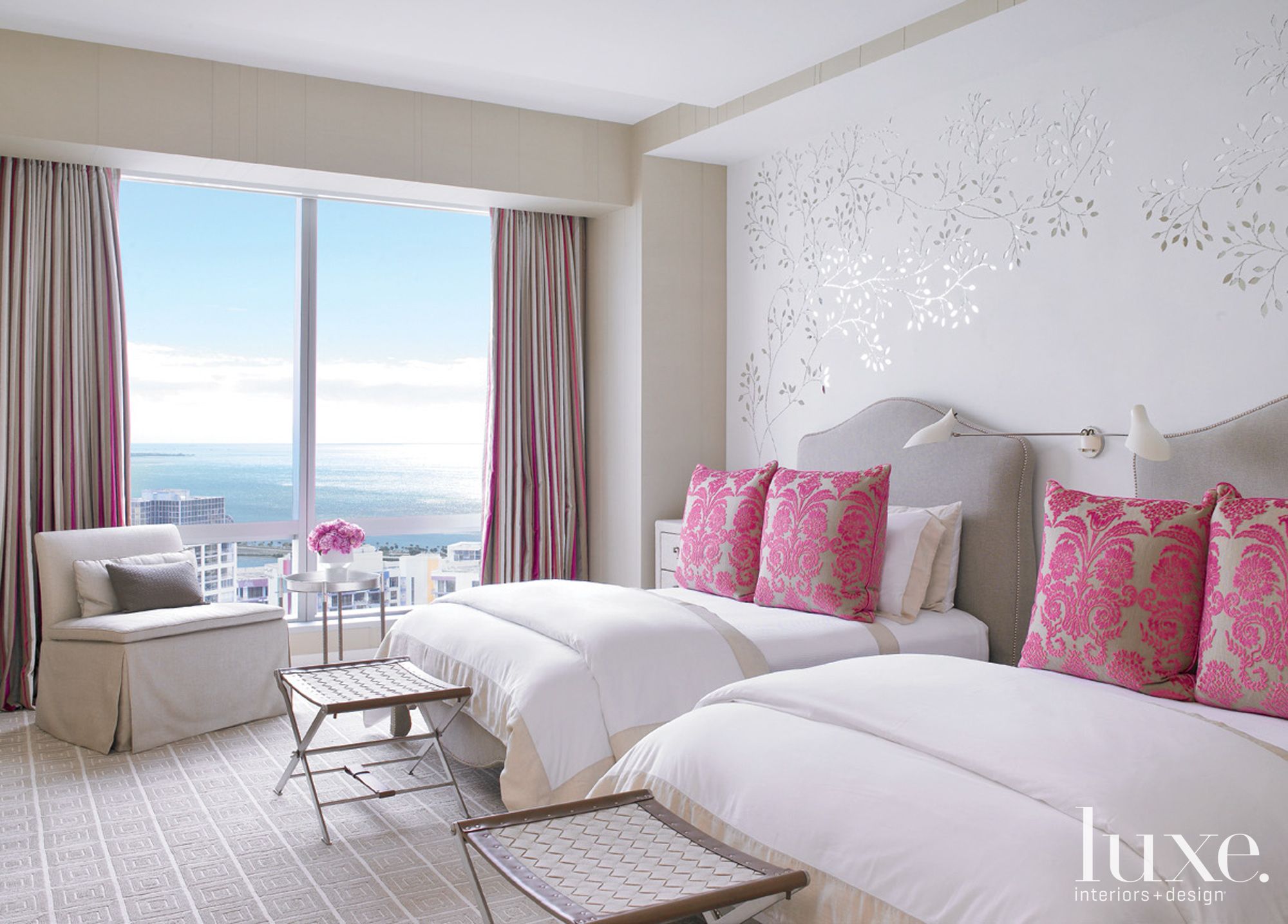 white bedroom with beds, pink curtains and pillows