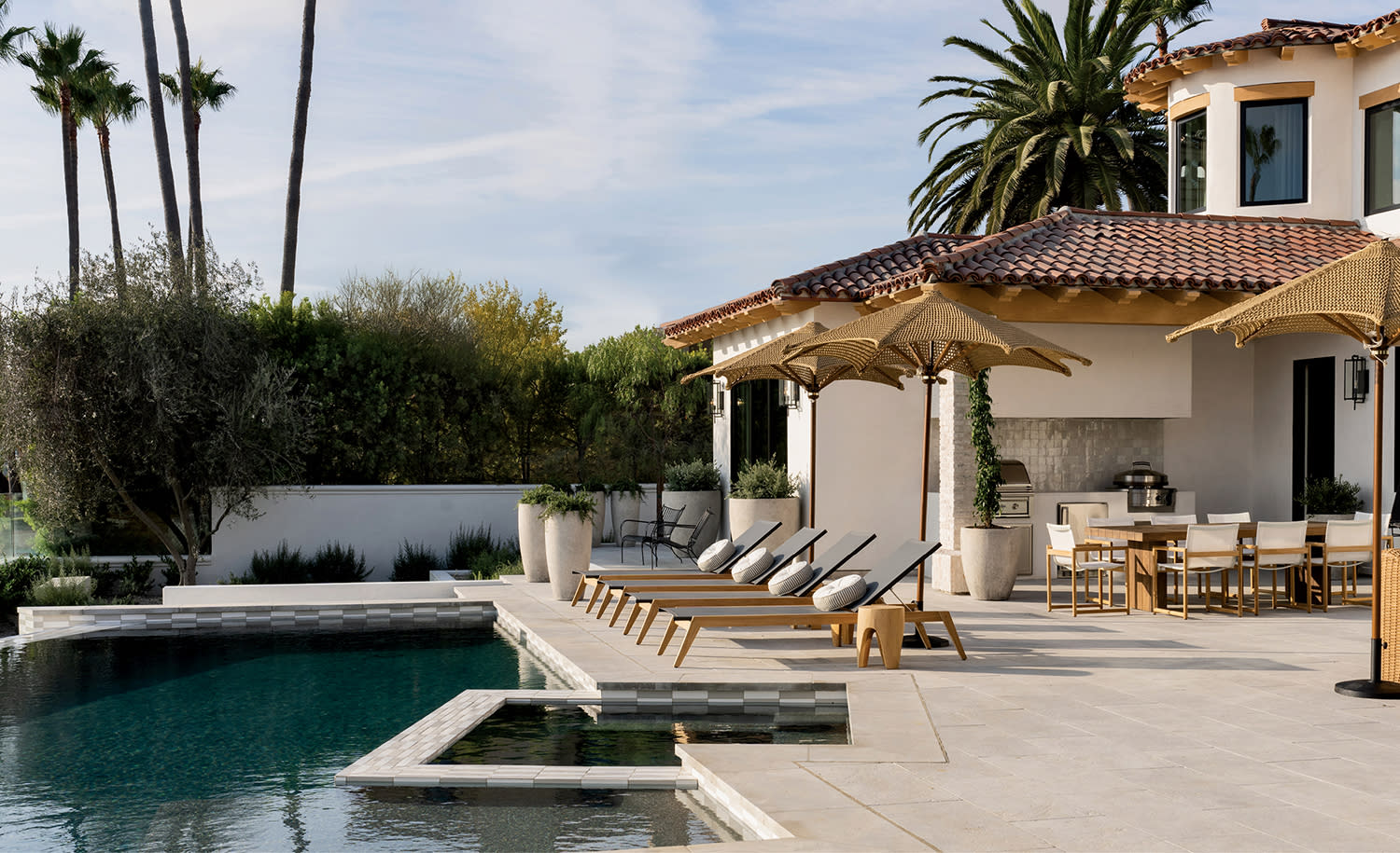 back exterior of a Spanish Revival-style home with a pool 