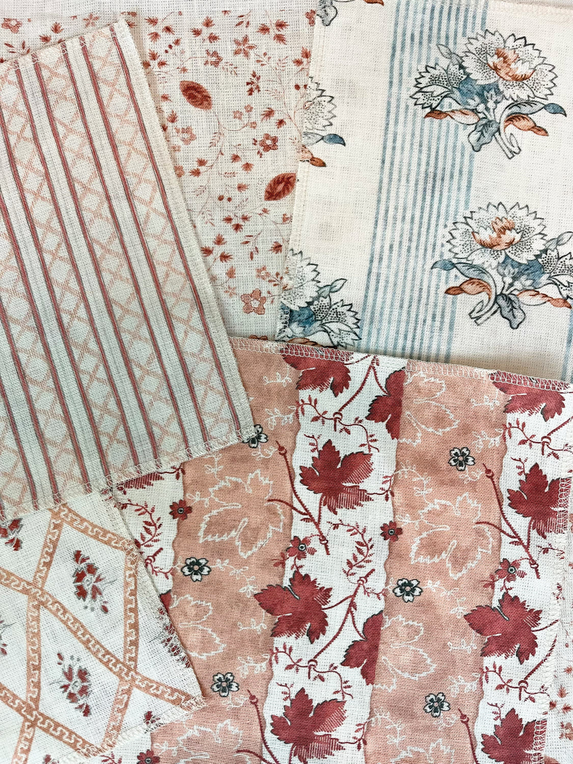 5 different textile samples of different floral patterns overlaid on top of each other.