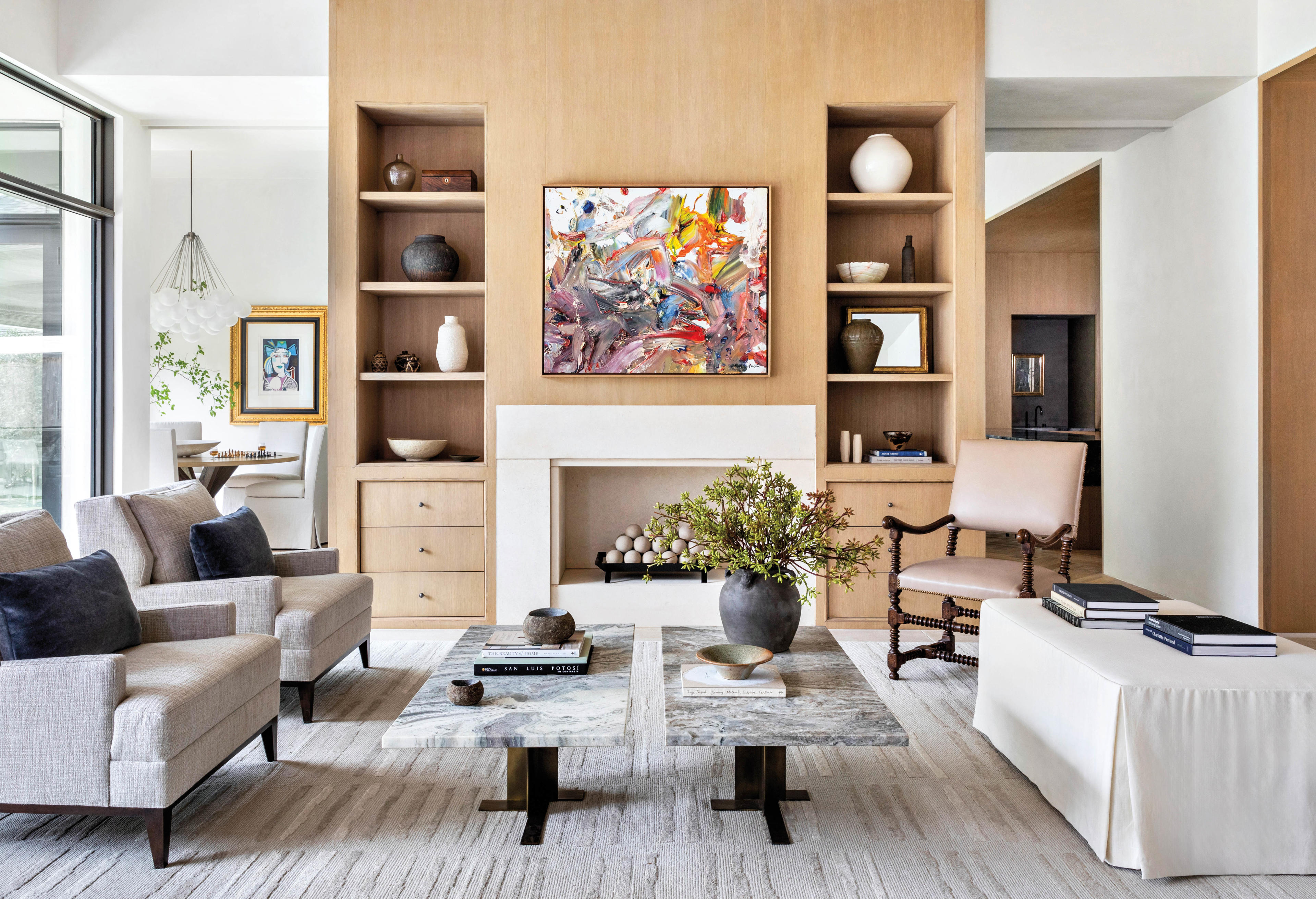 living room with white oak millwork, limestone fireplace surround and abstract art 