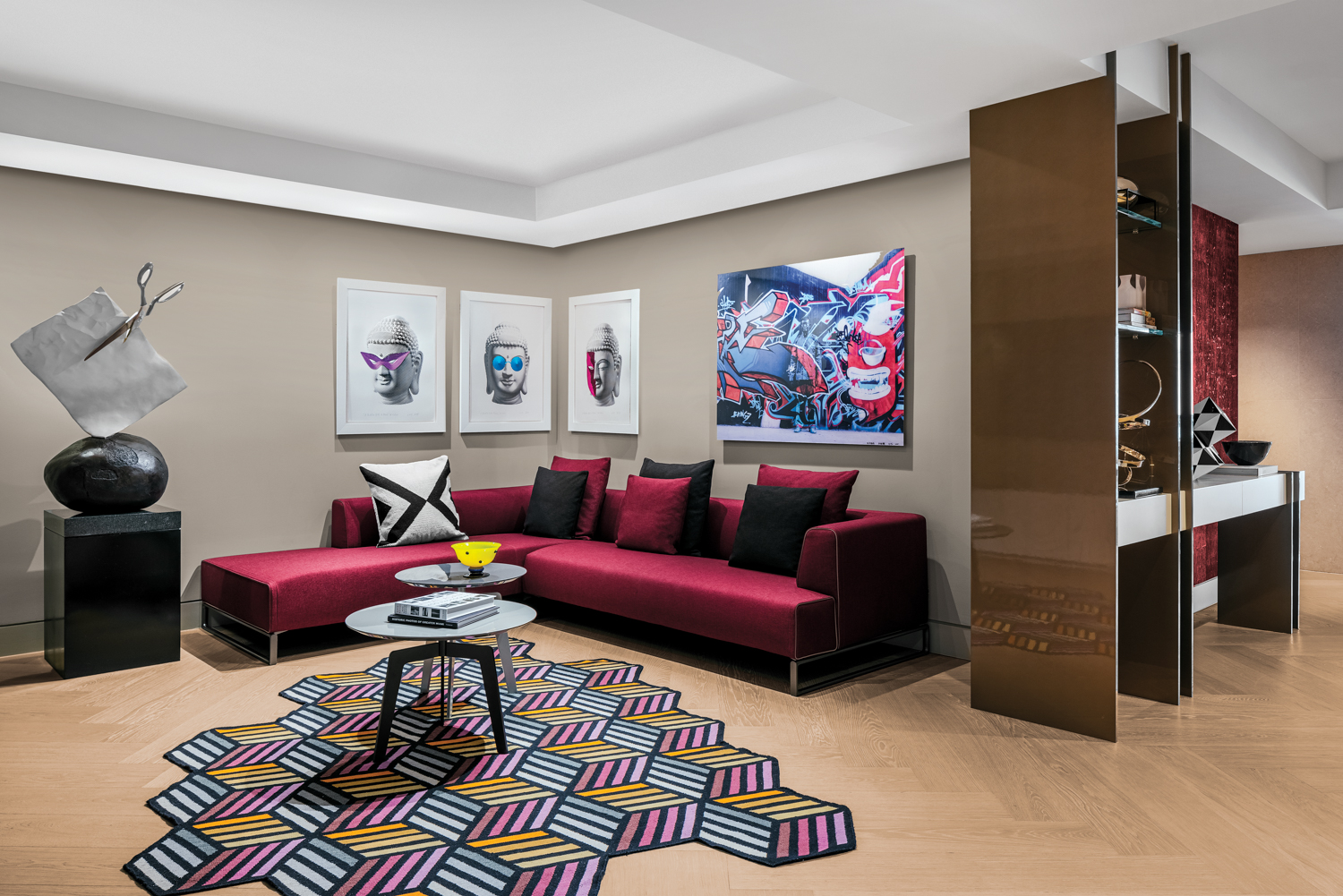 den with geometric rug, wood flooring, deep red sofa and contemporary wall artwork