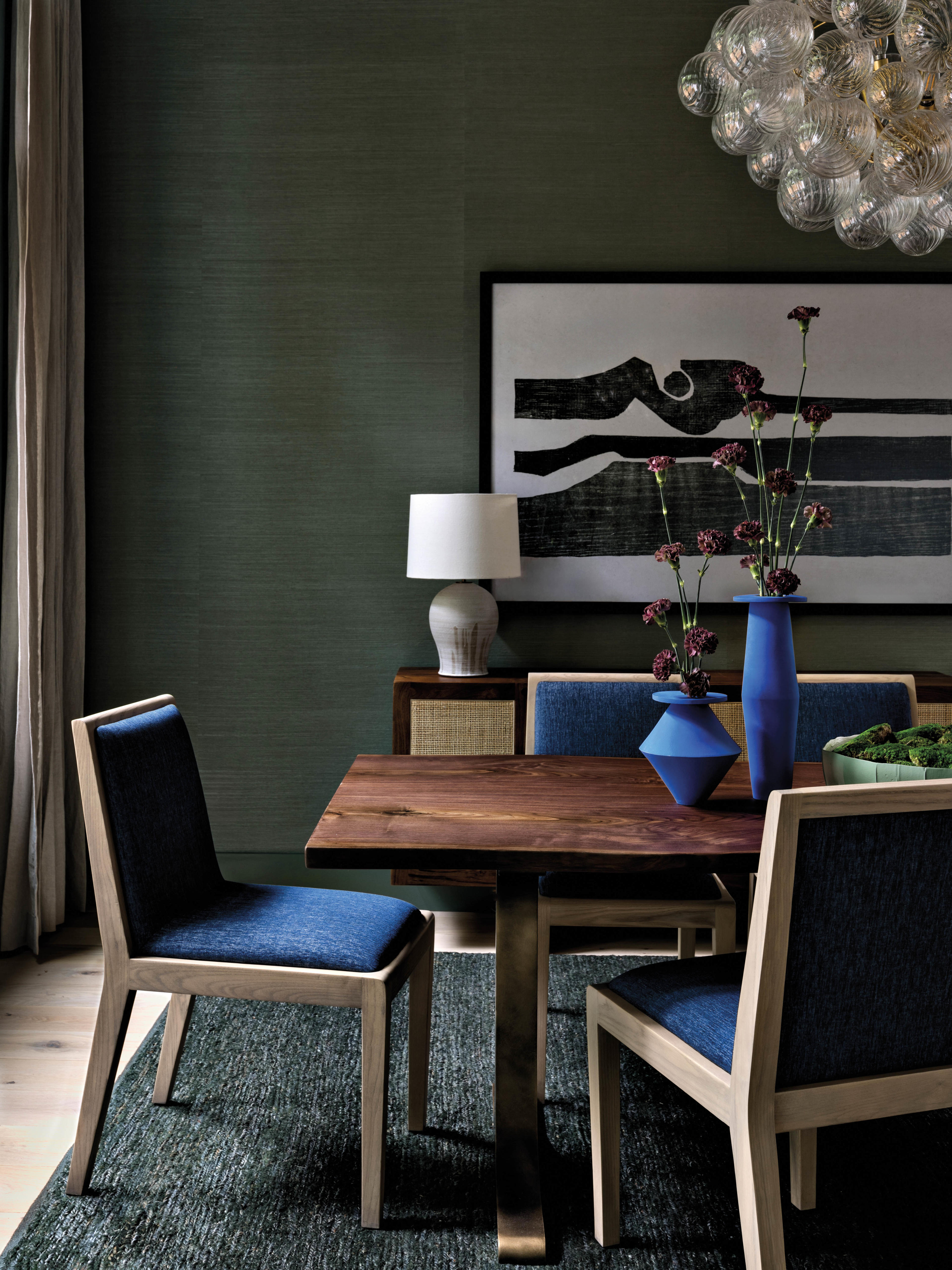 moody dining room with green walls and deep blue chairs