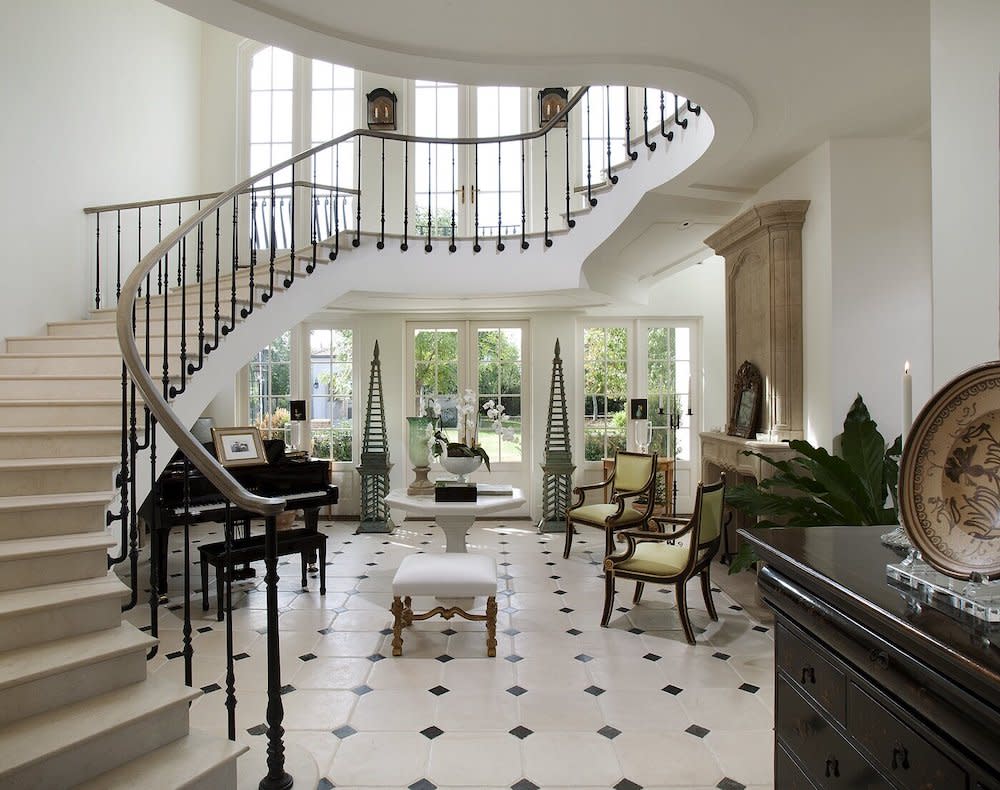 Foyer with curved staircase, black and white flooring, piano and fireplace