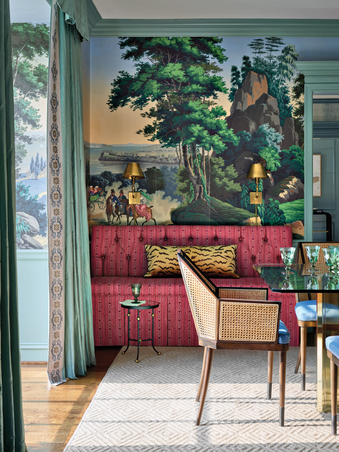 Blue and green dining room with hand-painted scenic wallpaper, red banquette seating and caned dining chairs