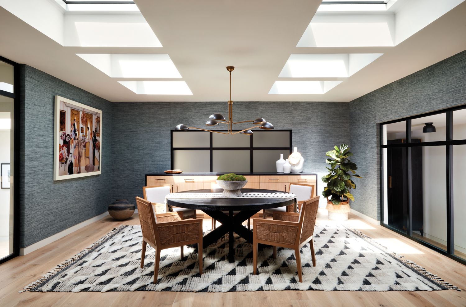 formal dining room with blue grasscloth covered walls and a custom round dining table ringed by armchairs