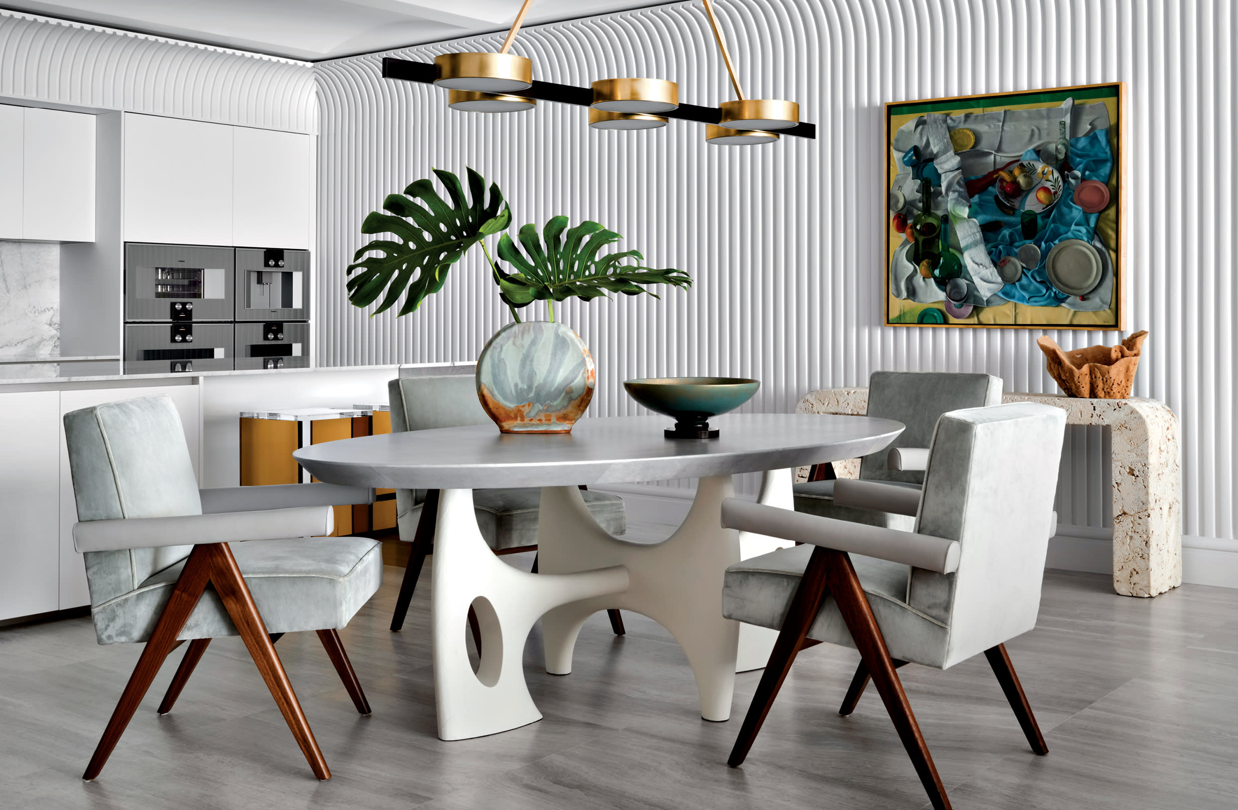 modern dining room with gray velvet chairs around a sculptural dining table