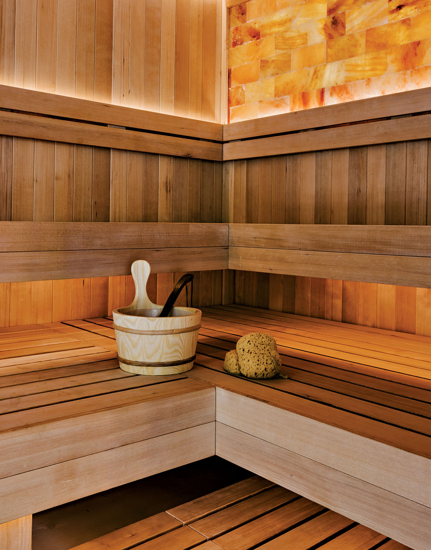 A sauna with wood benches and walls lined with squares of Himalayan salt.