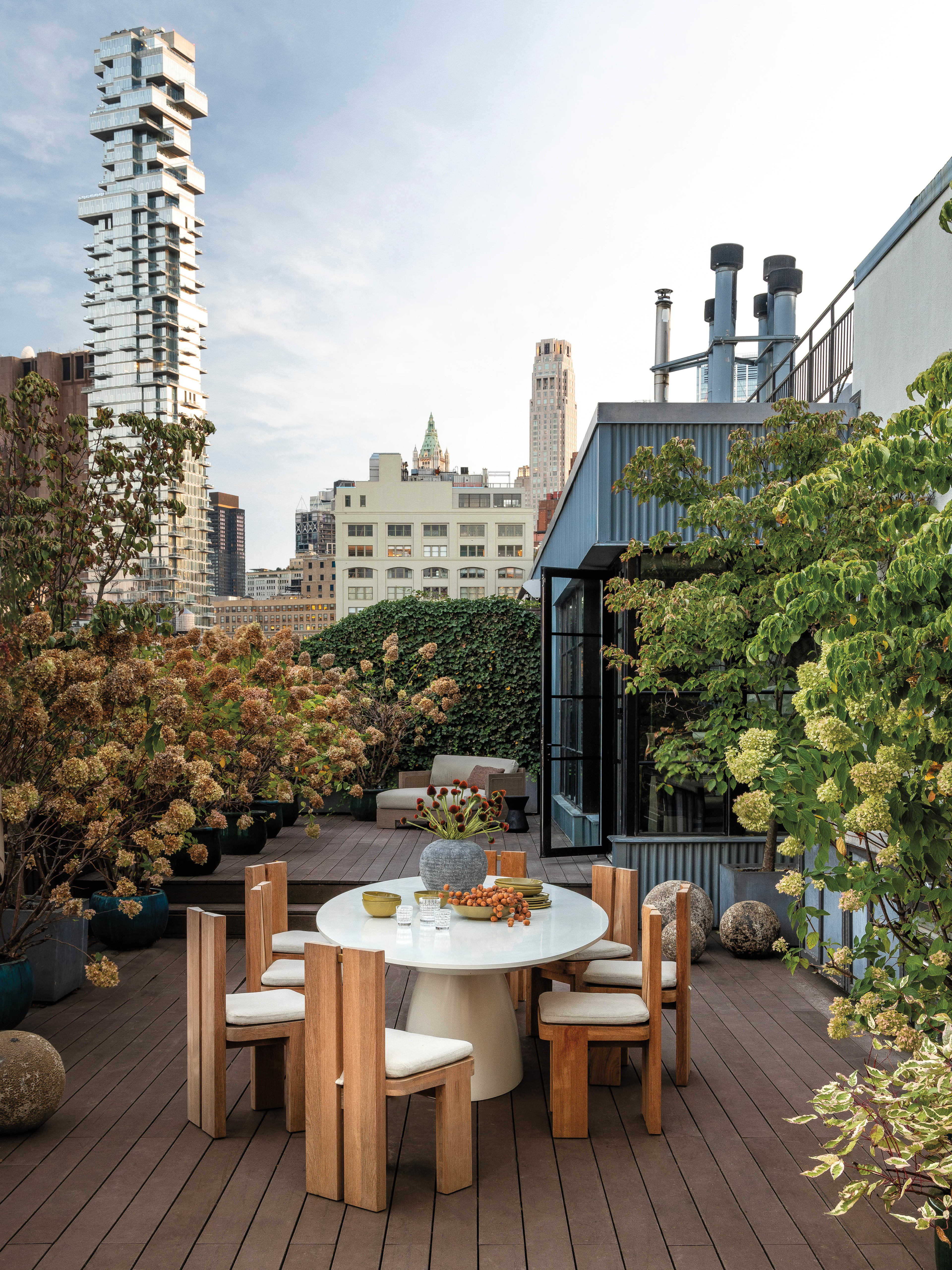 alfresco dining space on the terrace of a Tribeca home surrounded by plants and skyline views