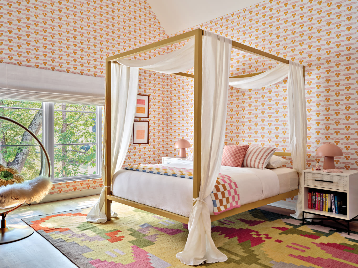 whimsical little girls bedroom with a orange and white wallcovering, canopy bed and colorful rug