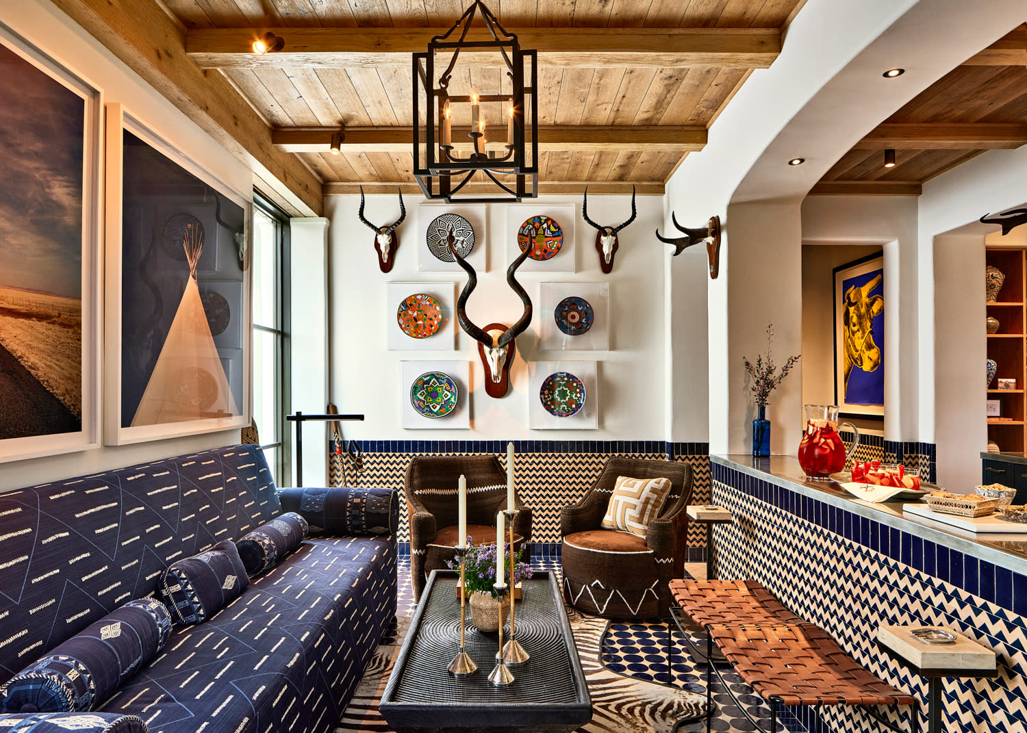 Eclectic living room with patterned blue furniture, decorative plates, and antler mounts on walls