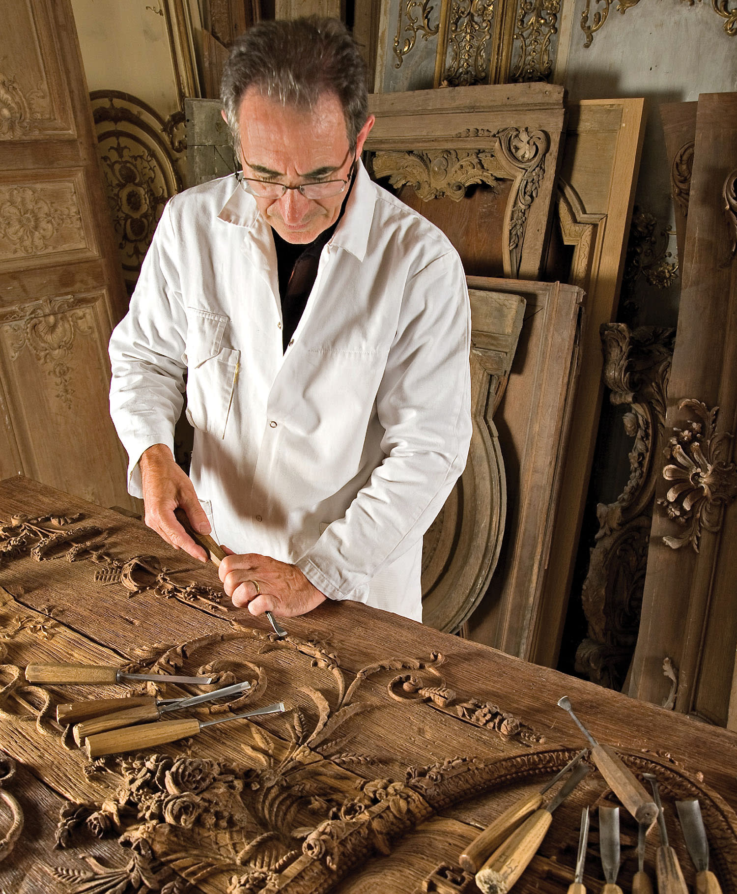 an artisan carves a wooden panel with traditional tools
