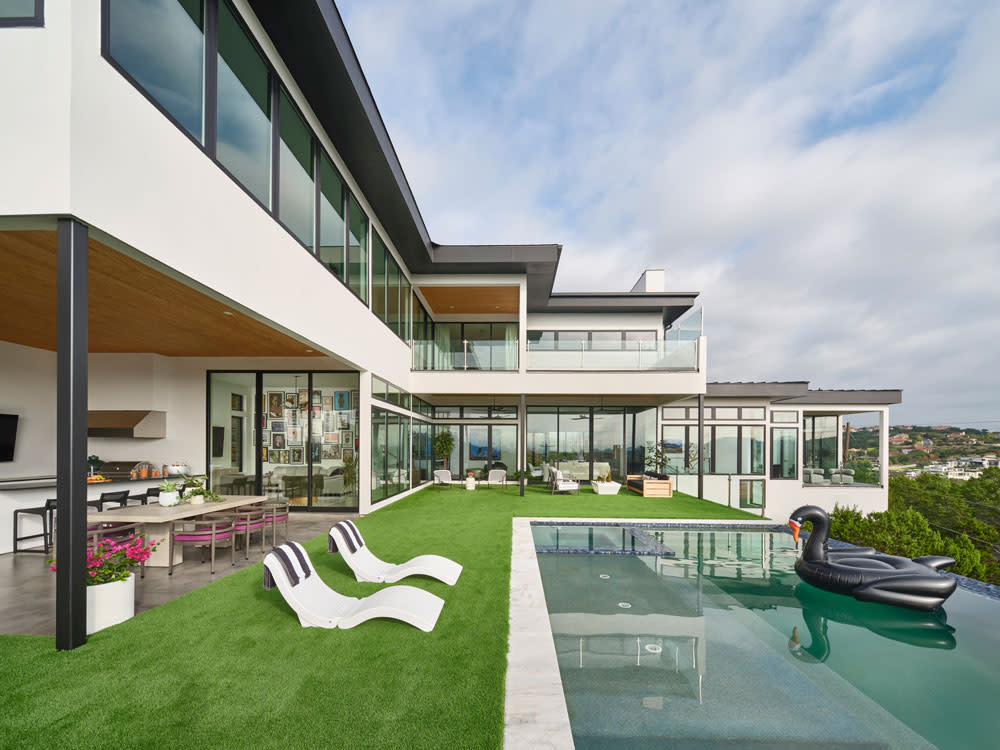 Glass doors open to this dream outdoor living space, featuring a stylish lounging area and sleek outdoor kitchen, all set against panoramic views of downtown Austin. Photography by Andrea Calo.