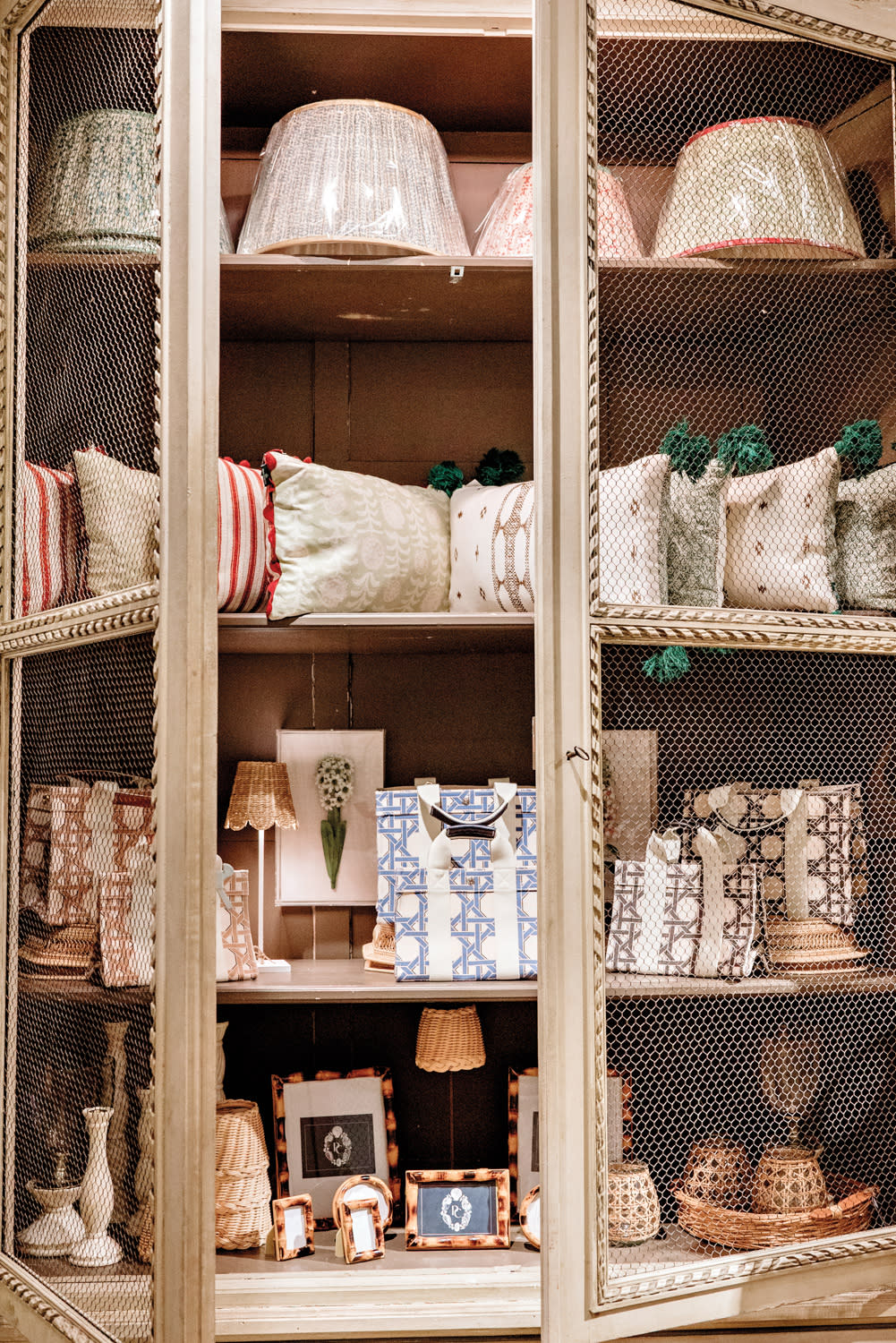 display cabinet filled with antiques, pillow cases, lampshades, and photo frames