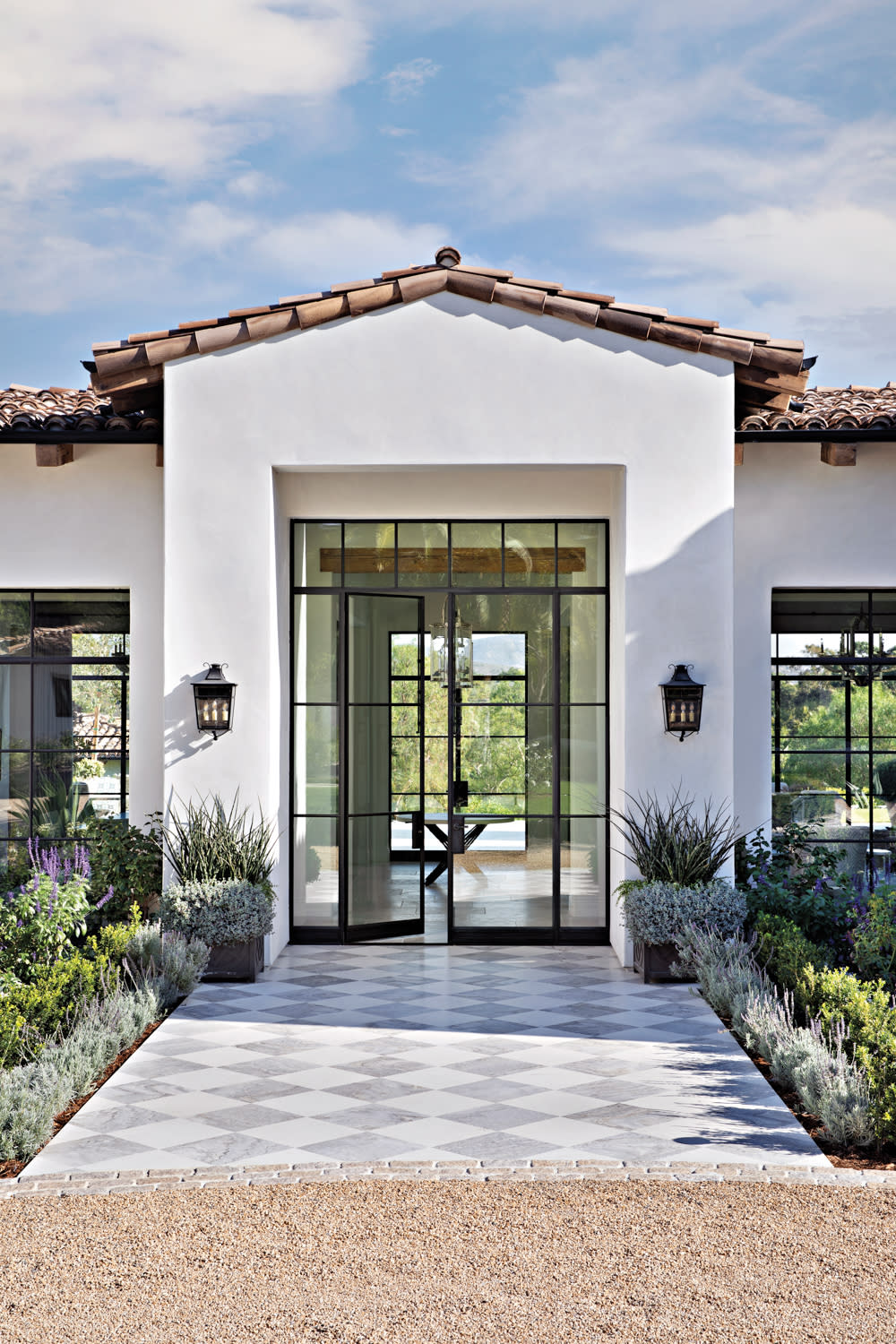 bespoke glass-and-metal entry door at end of checkerboard pattern tile pathway