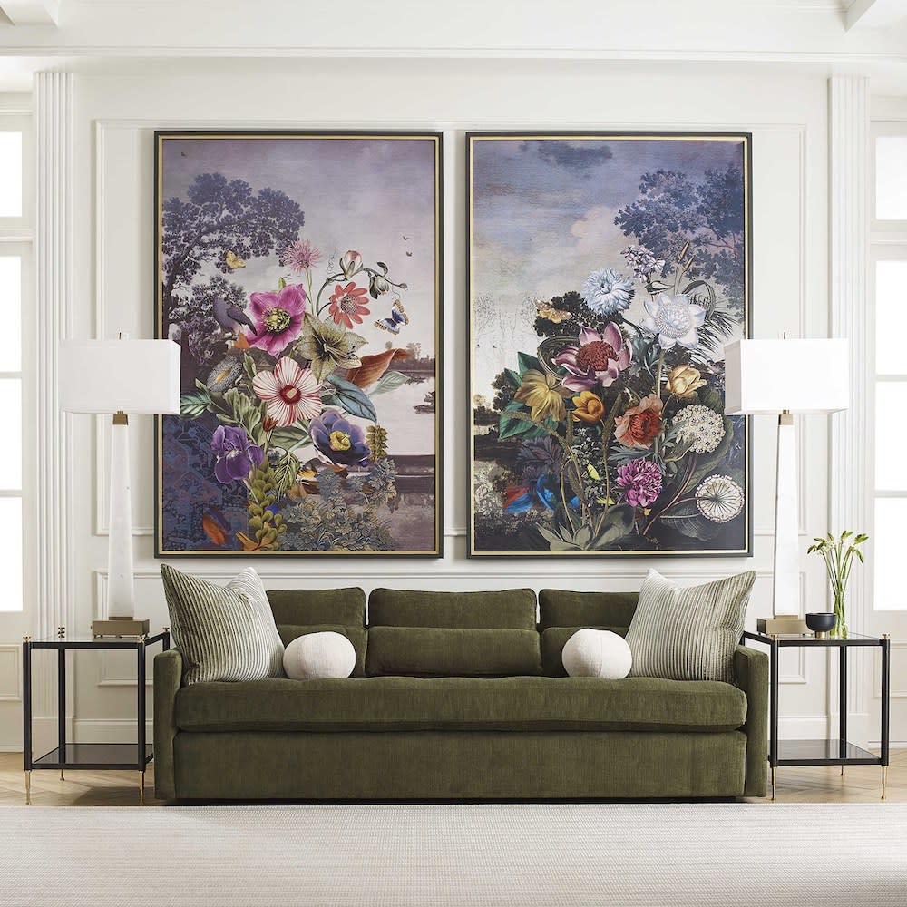 A well-decorated living room with two oversized paintings displayed above couch.