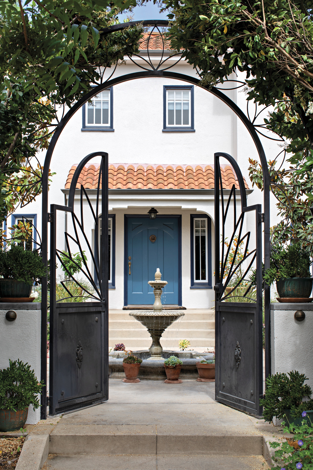 Mediterranean garden with arched iron gates and bird bath play into the modern garden landscape