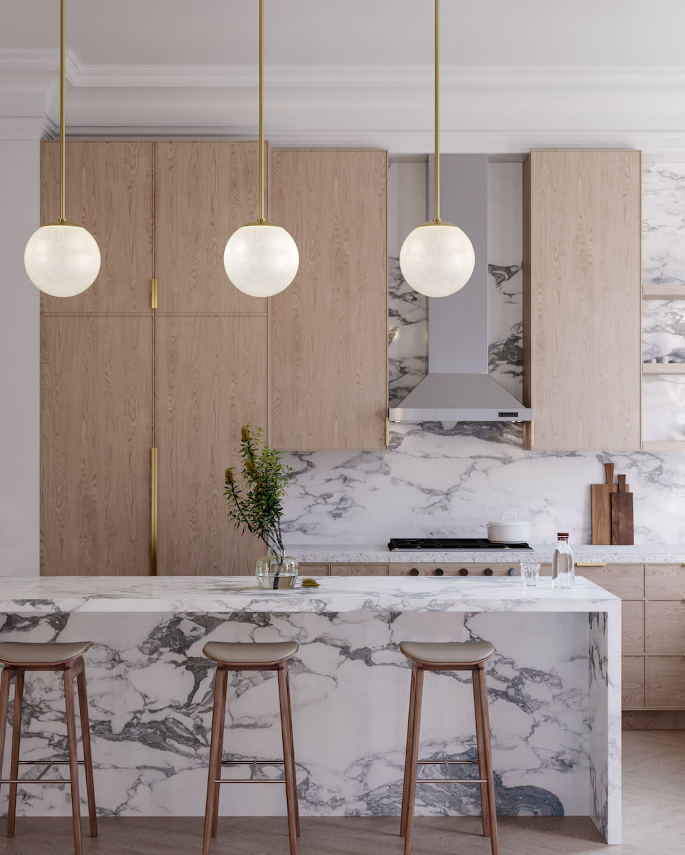 Sleek kitchen design with light wood cabinets, brass hardware, gray and white marble countertops, and pendant lighting.