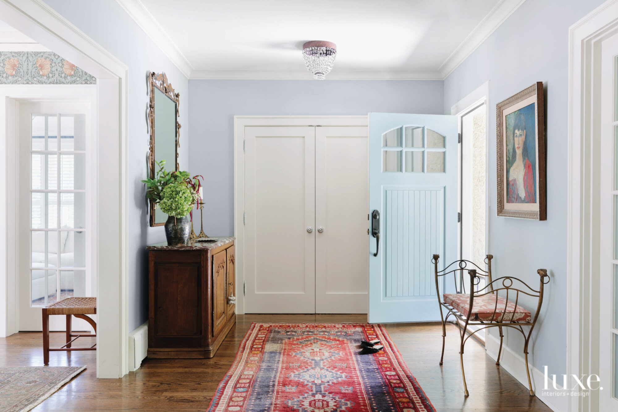 A colorful runner and a blue farmhouse door welcome visitors into the home's entryway