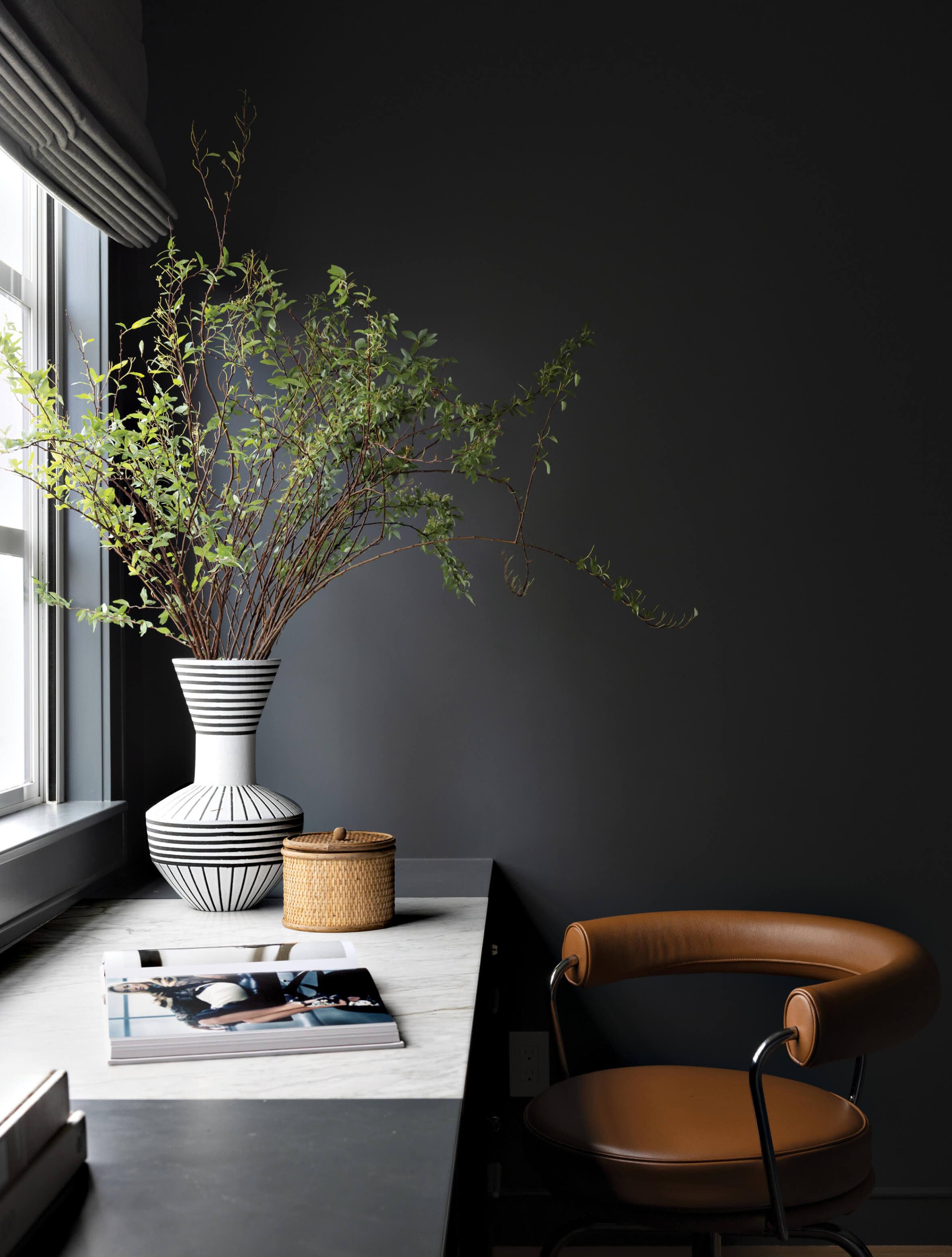 moody desk area with black walls and a leather chair