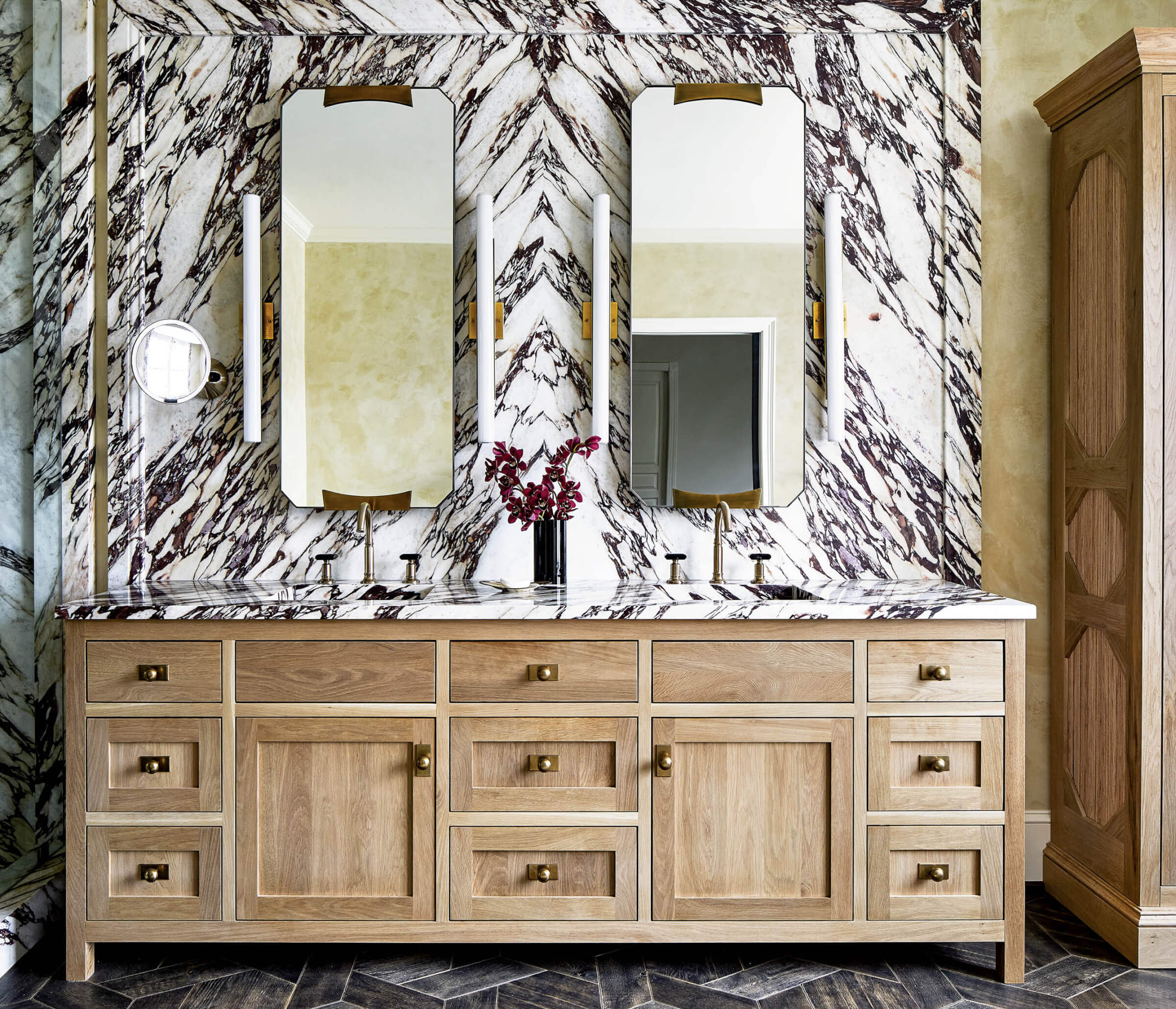 light wood vanity against a luxurious brown and white marble backsplash in a bathroom