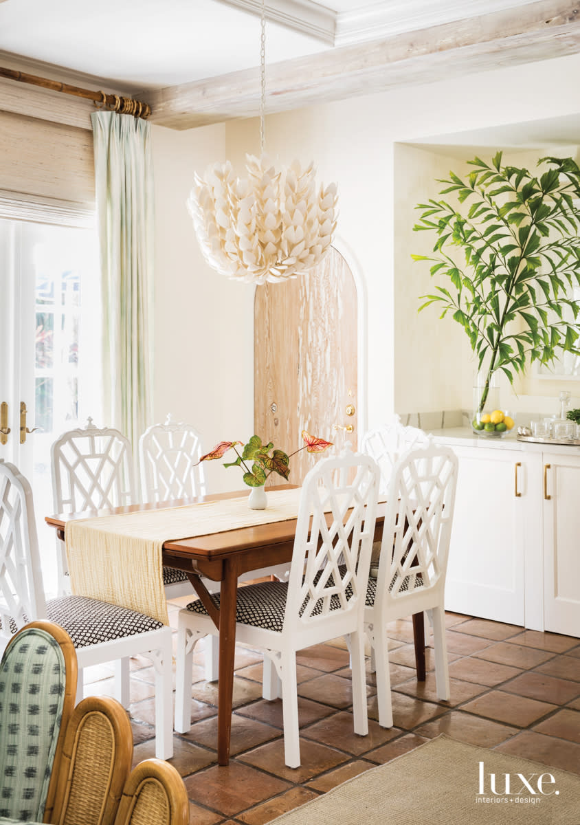 dining area with pendant, white chairs a teak table and terra-cotta flooring
