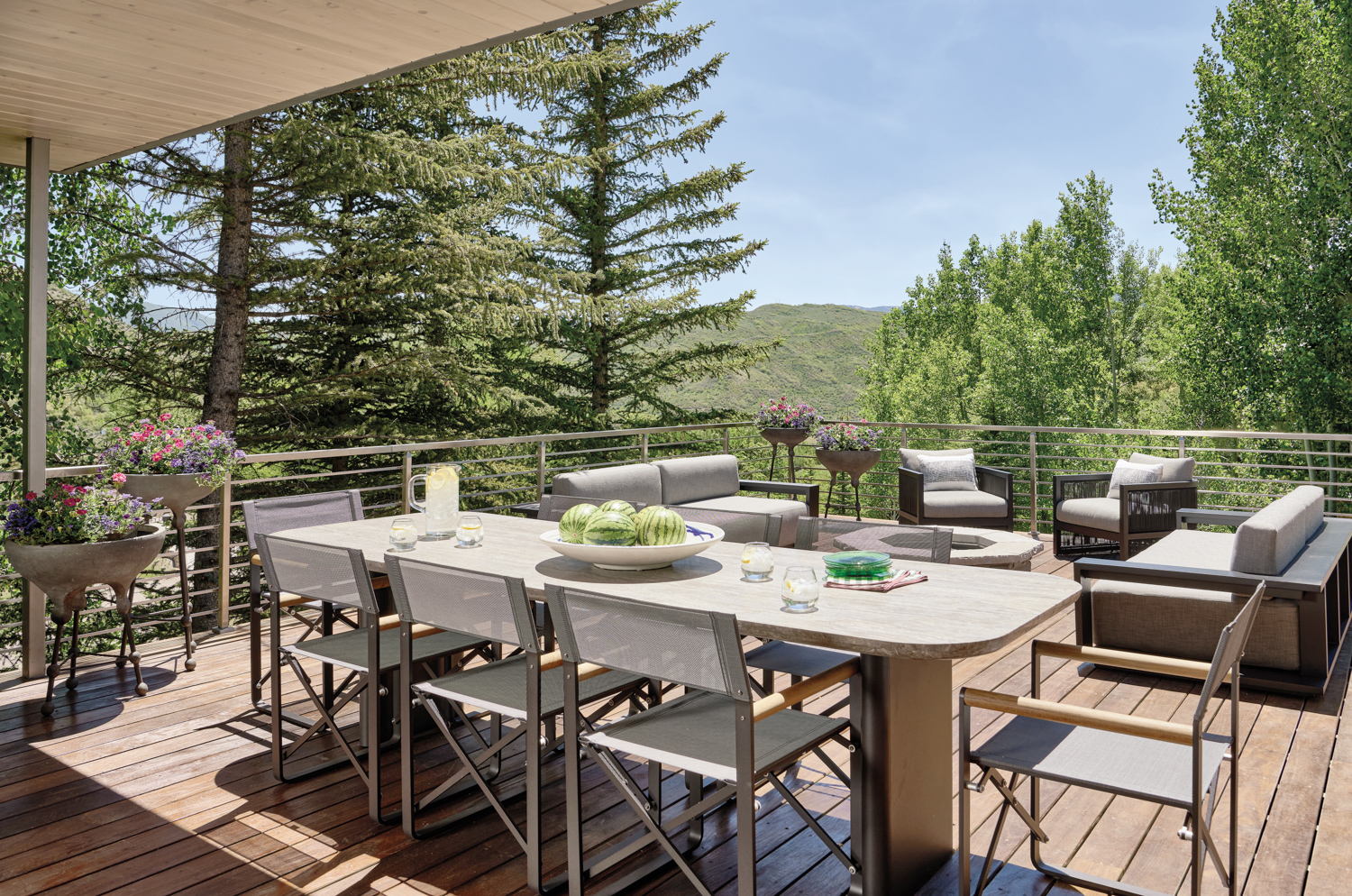 deck with outdoor table and dining chairs, firepit and armchairs in home by Kristin Dittmar Doremus