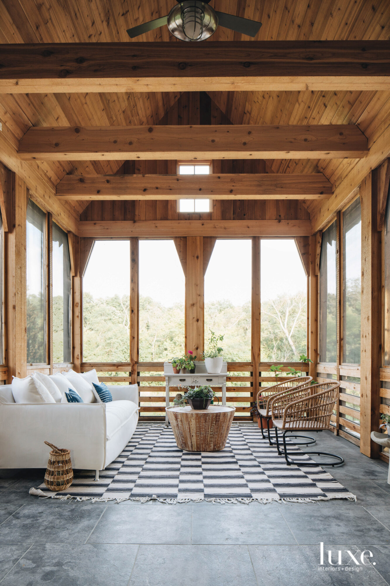 An indoor-outdoor room is framed by wooden beams that give it a cabin-feel.