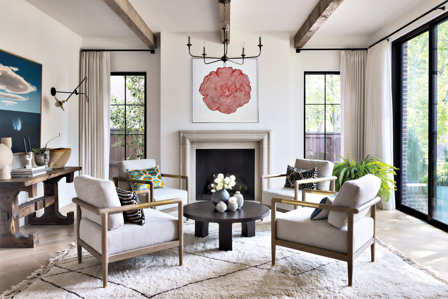 living room with fireplace, armchairs, black cocktail table and chandelier inspired by Axel Vervoordt