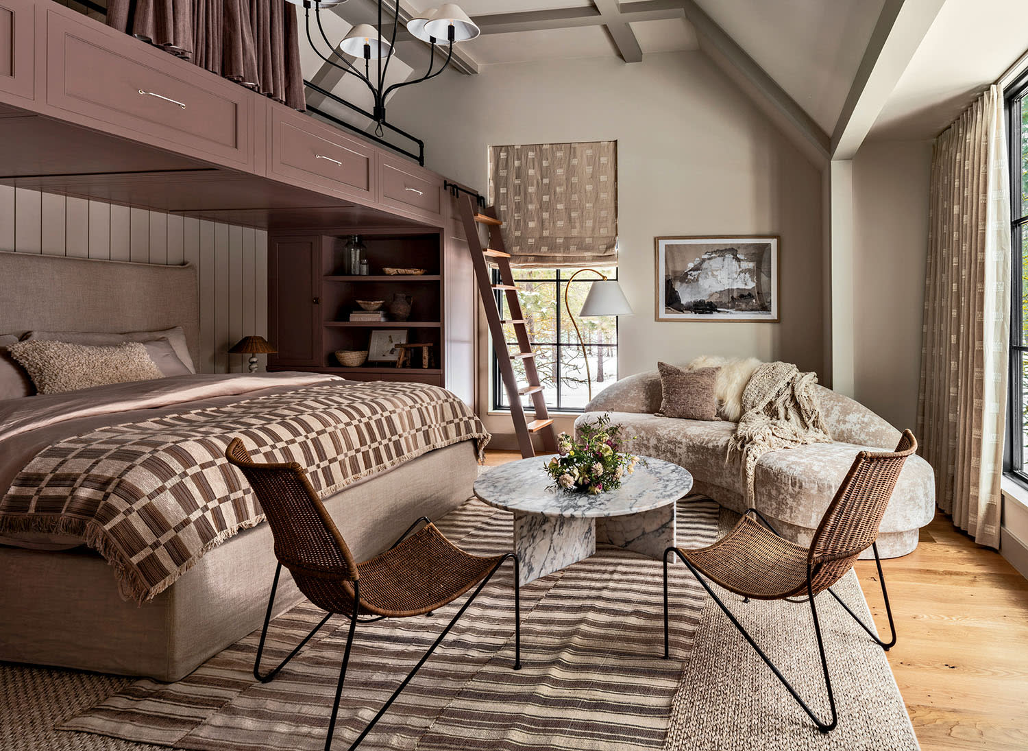 A bed in a guest suite surrounded by an upper bunk bed, a corner sofa and nearby table.