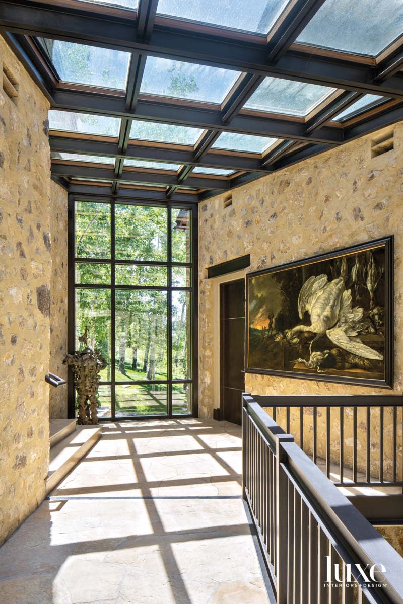 A passageway is lined with stoned and topped with a glass ceiling.