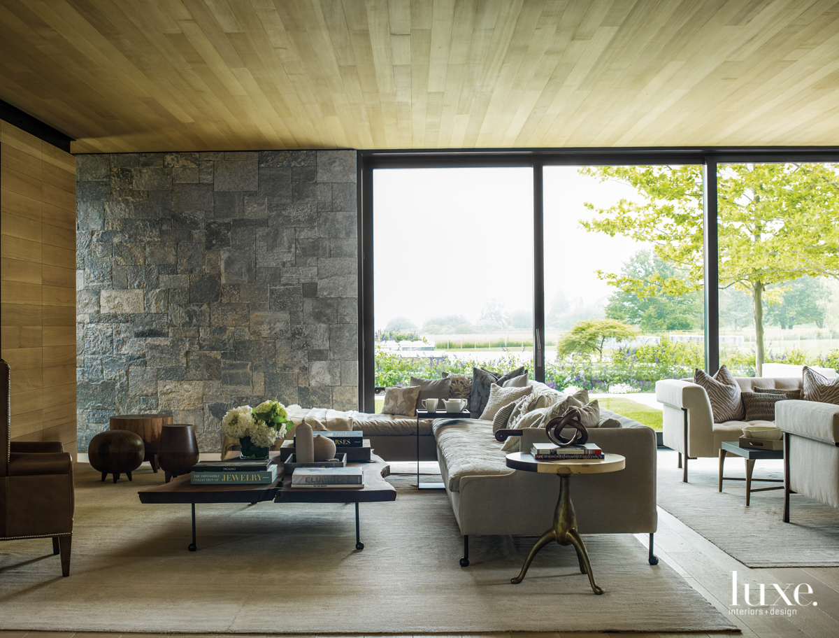 open living room with black frame windows, modern furniture and stone wall