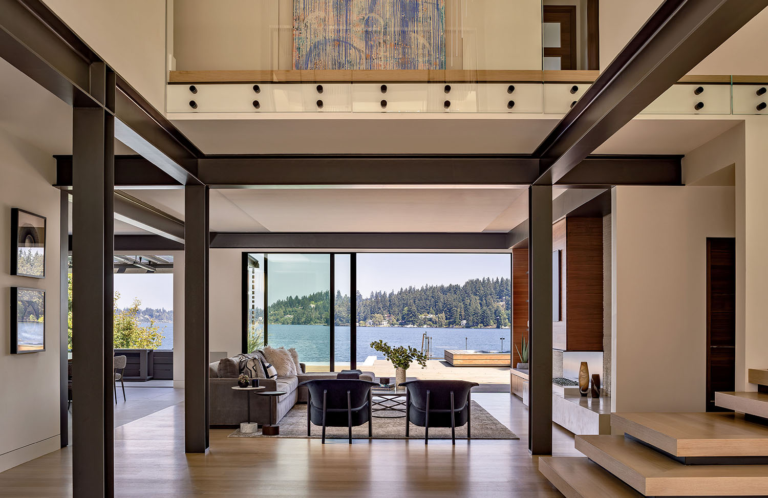 A living room outfitted with steel frames and a sitting area that looks out at the water.