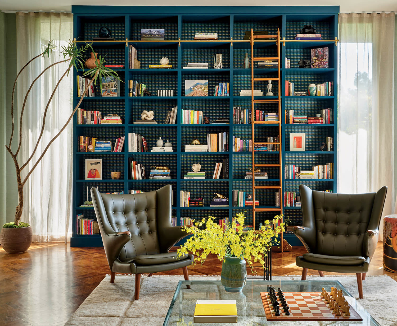 dark blue built-in with a rolling ladder behind green leather armchairs