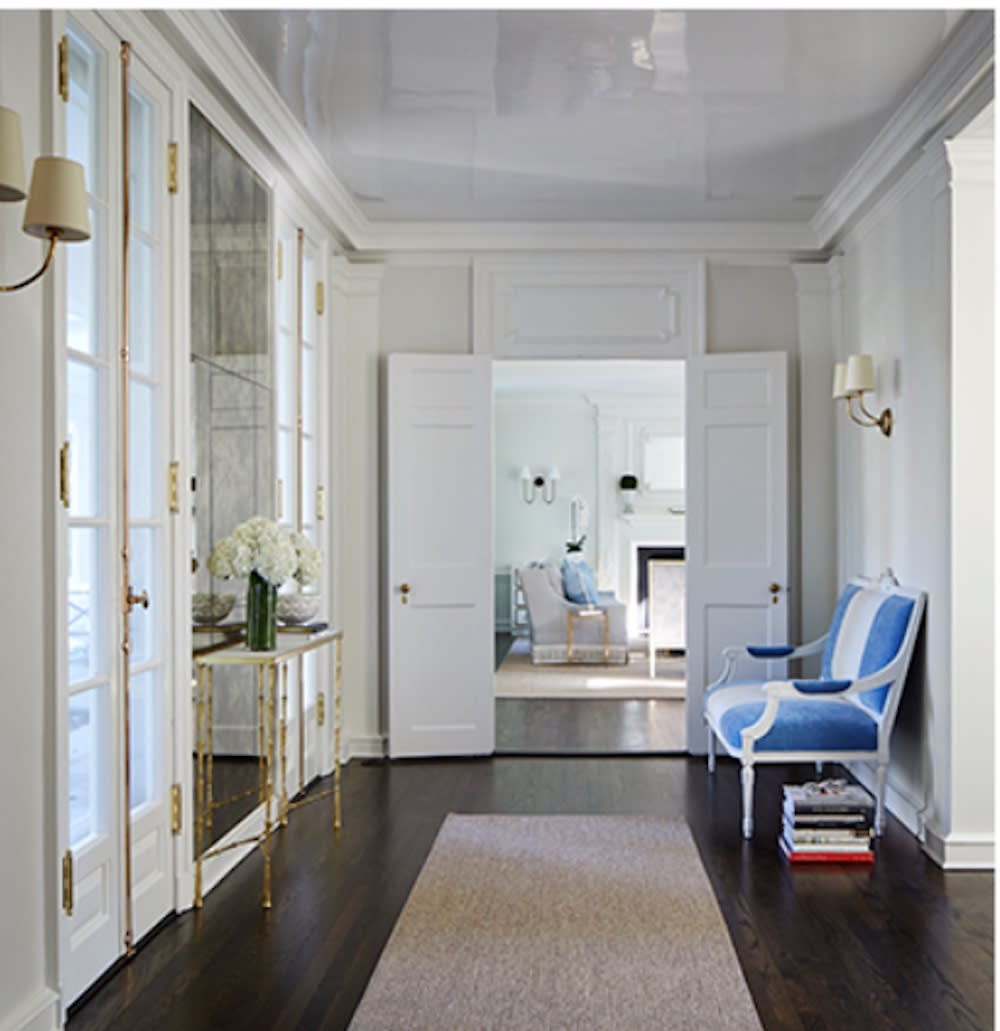 This chic hallway has double doors leading to living room. French doors to the outside, blue and white high back bench, high gloss white ceiling.