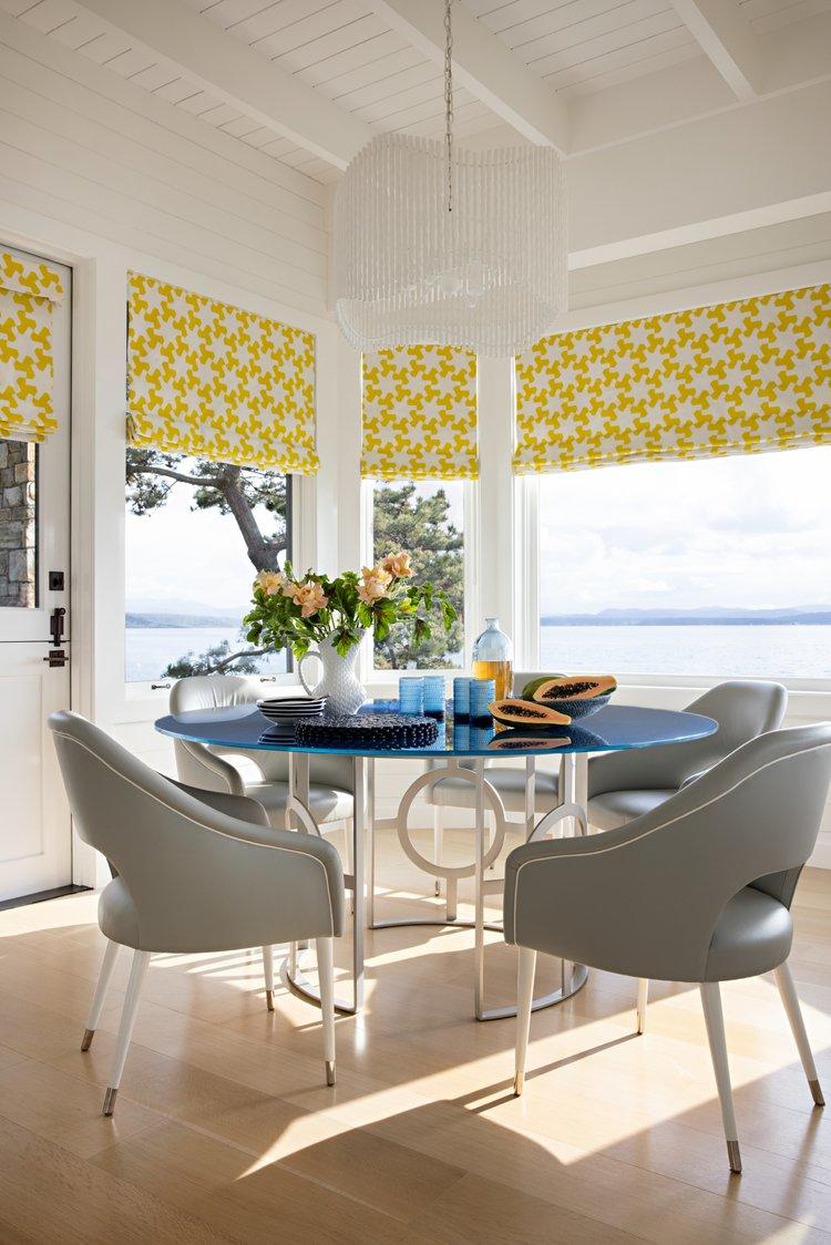 modern white dining space with blue table and yellow accent curtains by julie kleiner