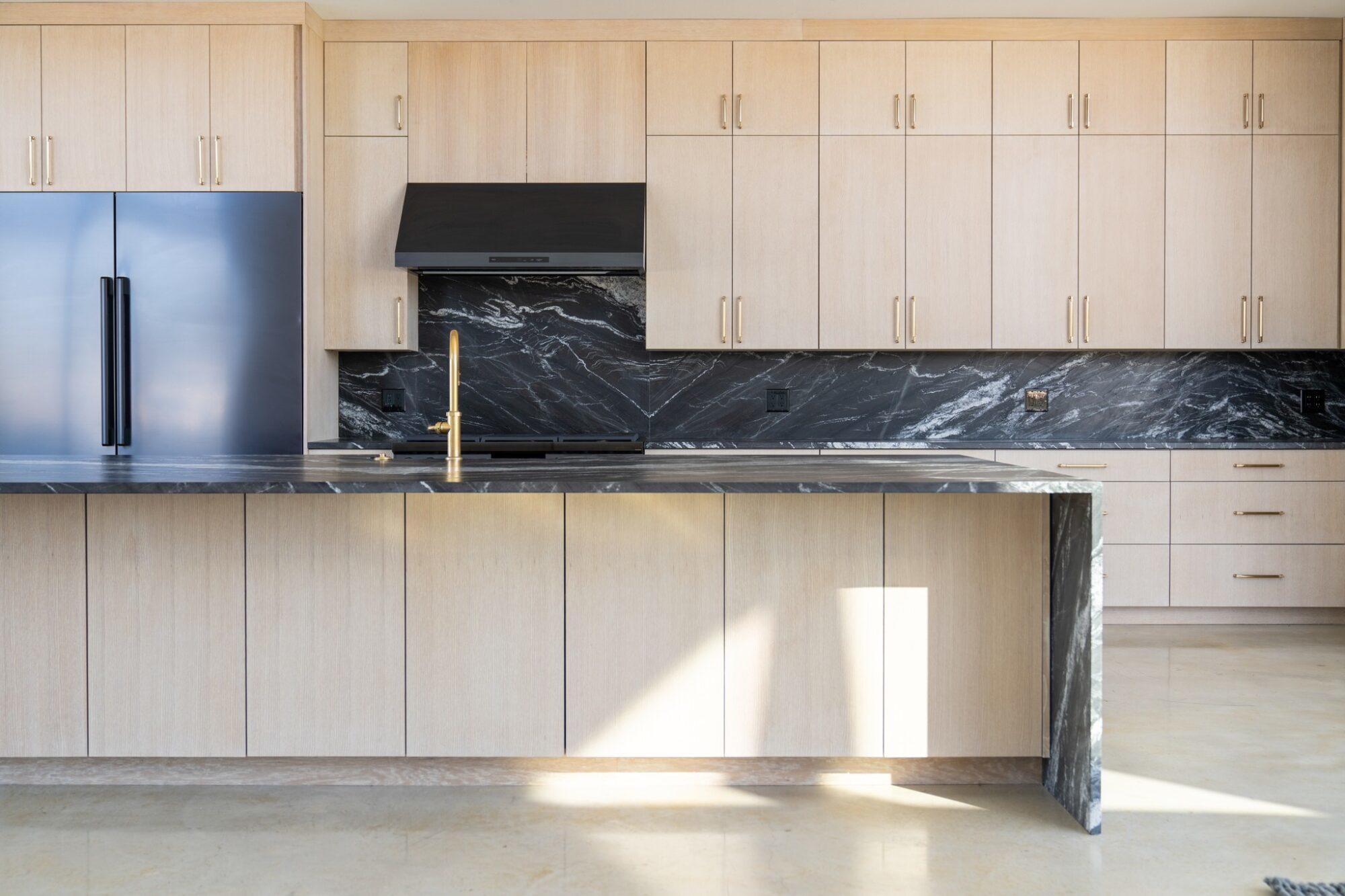 a kitchen with black marble counter tops and black refrigerator