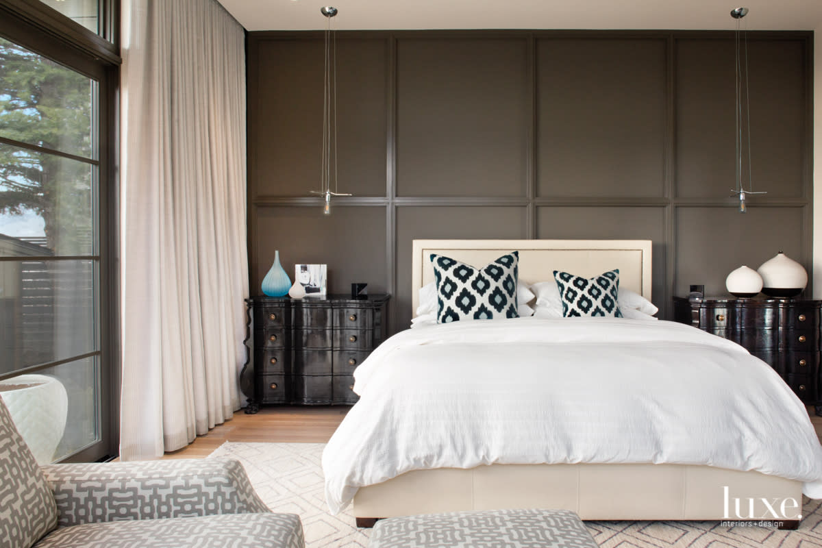 The master bedroom features a dark-gray accent wall behind a bed dressed in white linens.